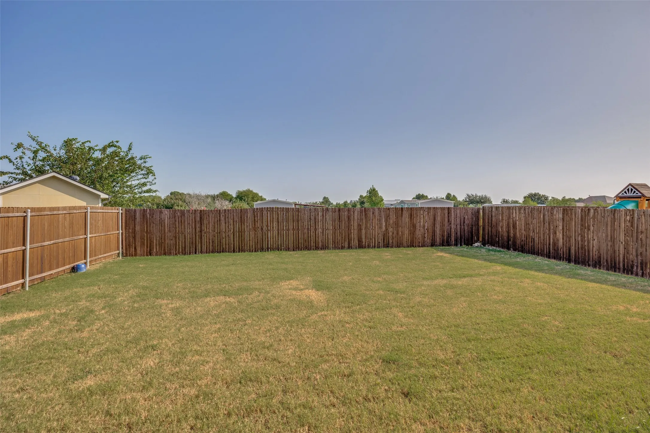 Spacious backyard featuring a manicured lawn and privacy fencing