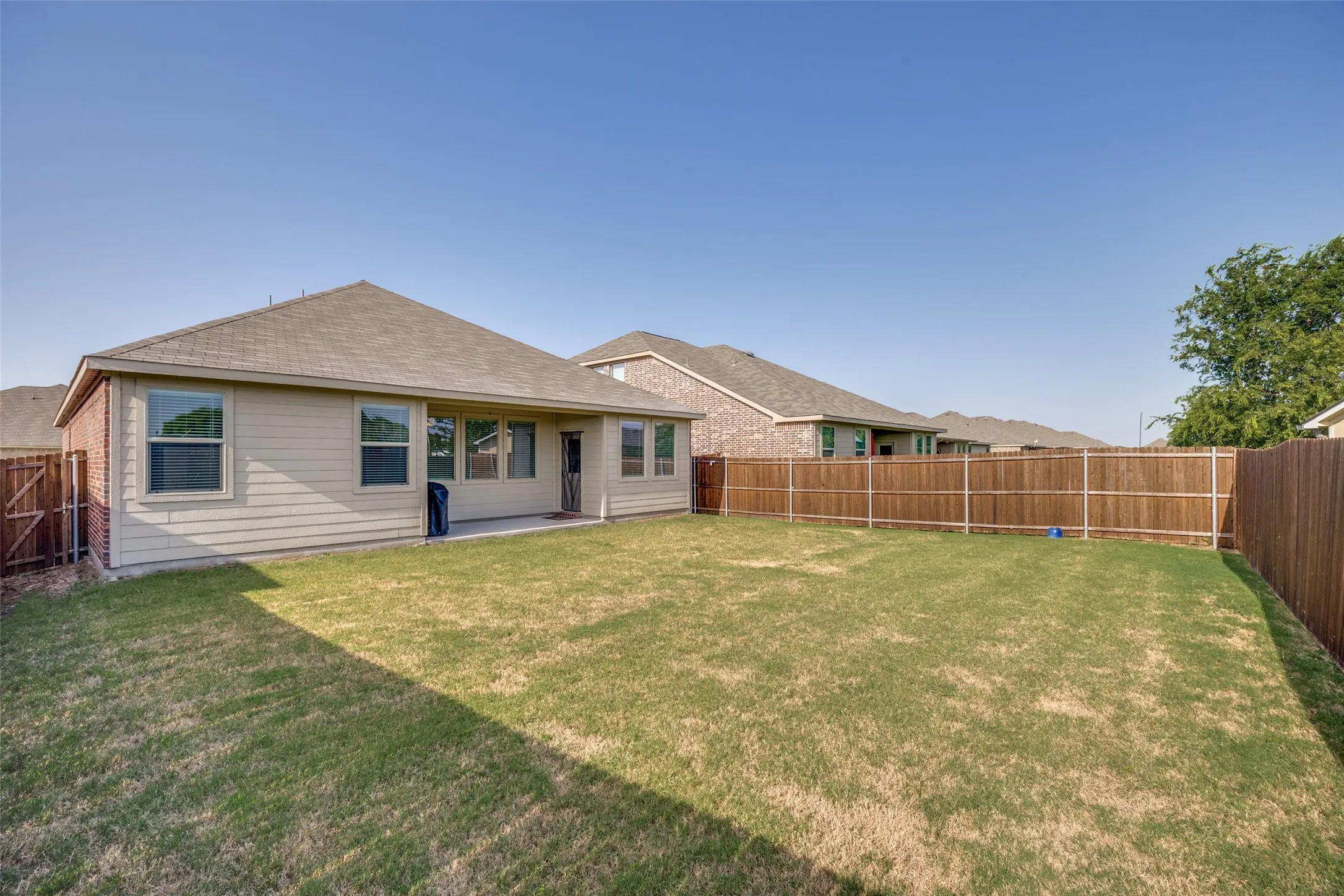 Spacious backyard featuring a privacy fence, a grass lawn, and a concrete patio