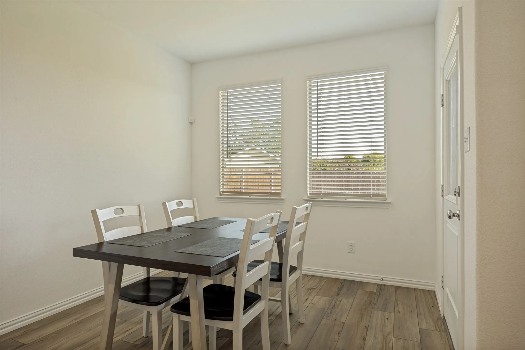 Dining area with light-colored walls and wood-finish flooring