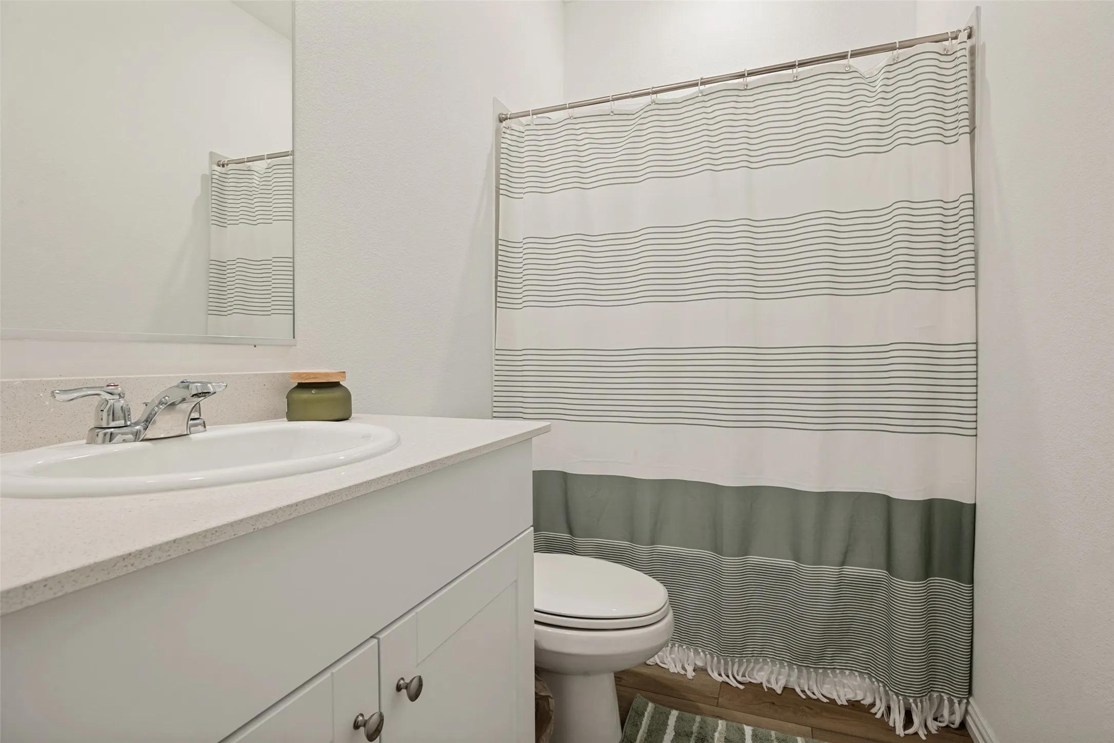 Bathroom featuring a white vanity with a white countertop and an integrated sink, polished chrome faucet, and a large wall-mounted mirror