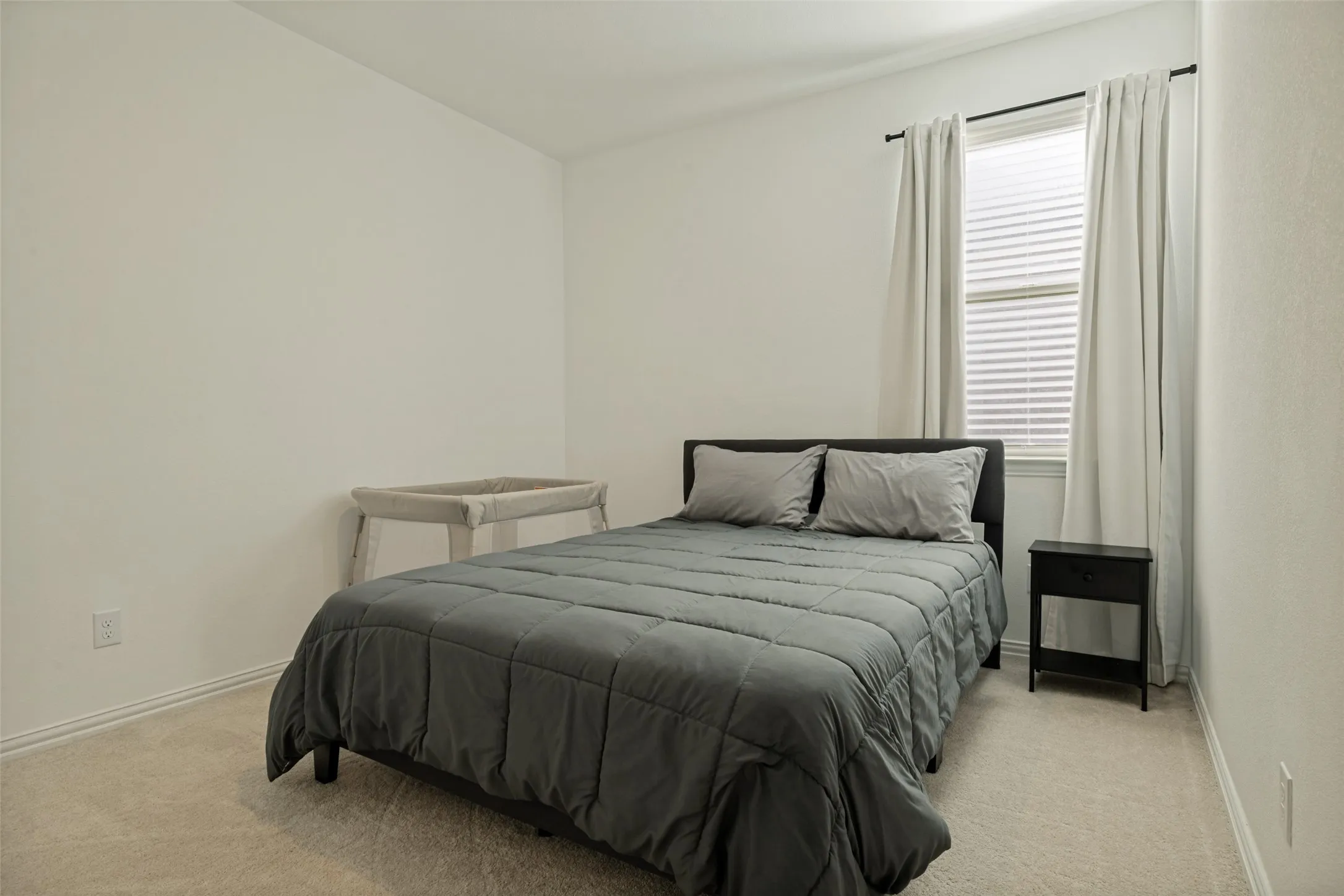 Carpeted room featuring a window with blinds and curtains