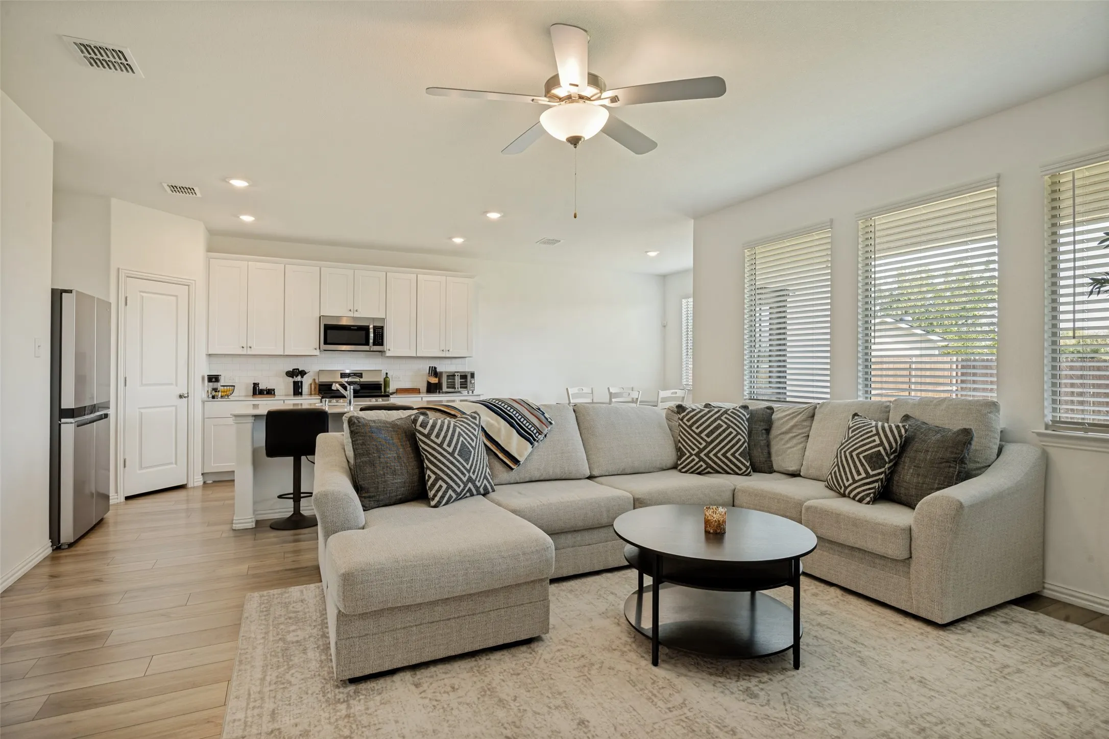 Open-concept living space featuring wood-finish flooring, recessed lighting, and a ceiling fan