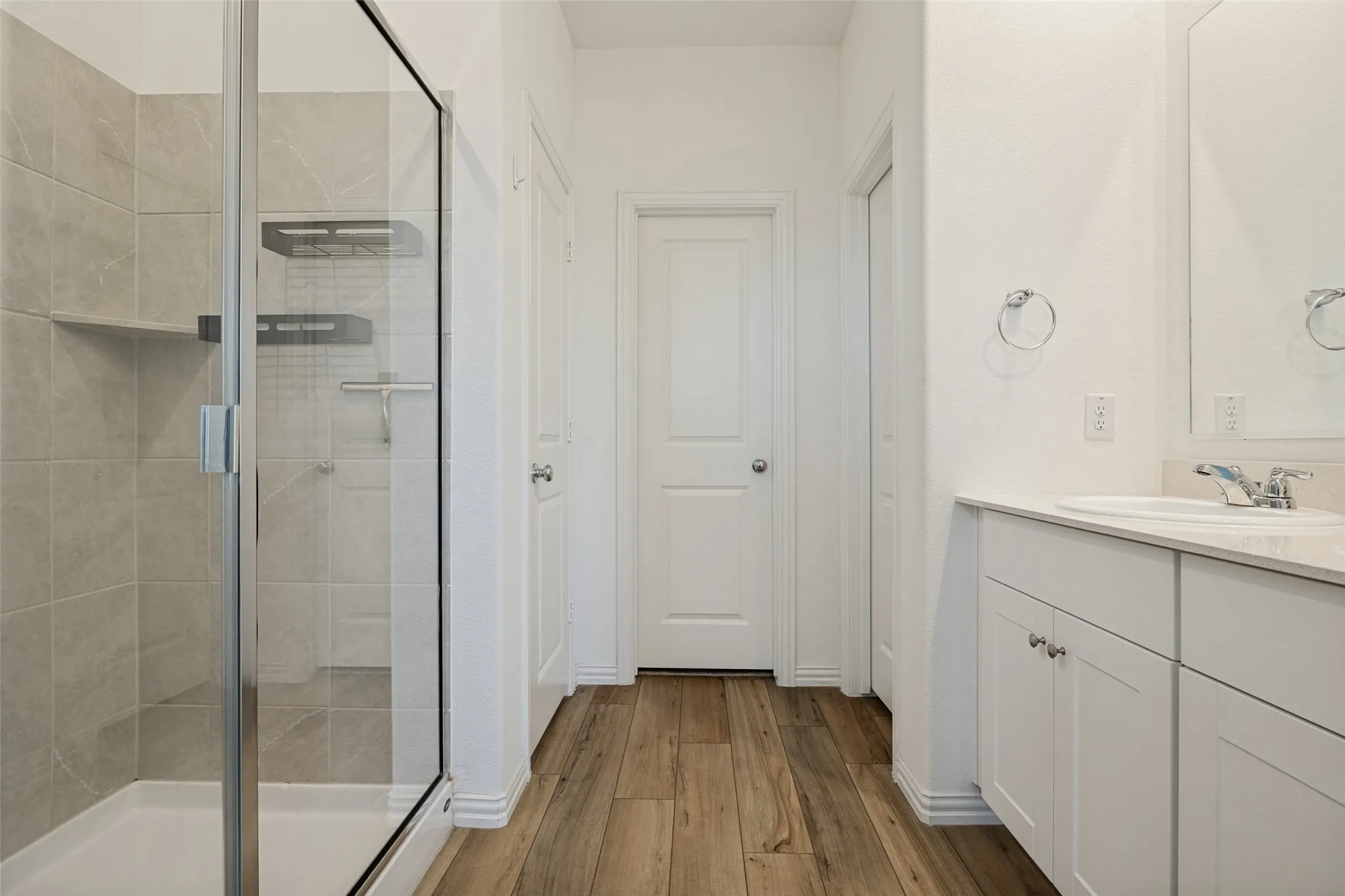Shower with glass enclosure, light-toned tile surround, and built-in shelving