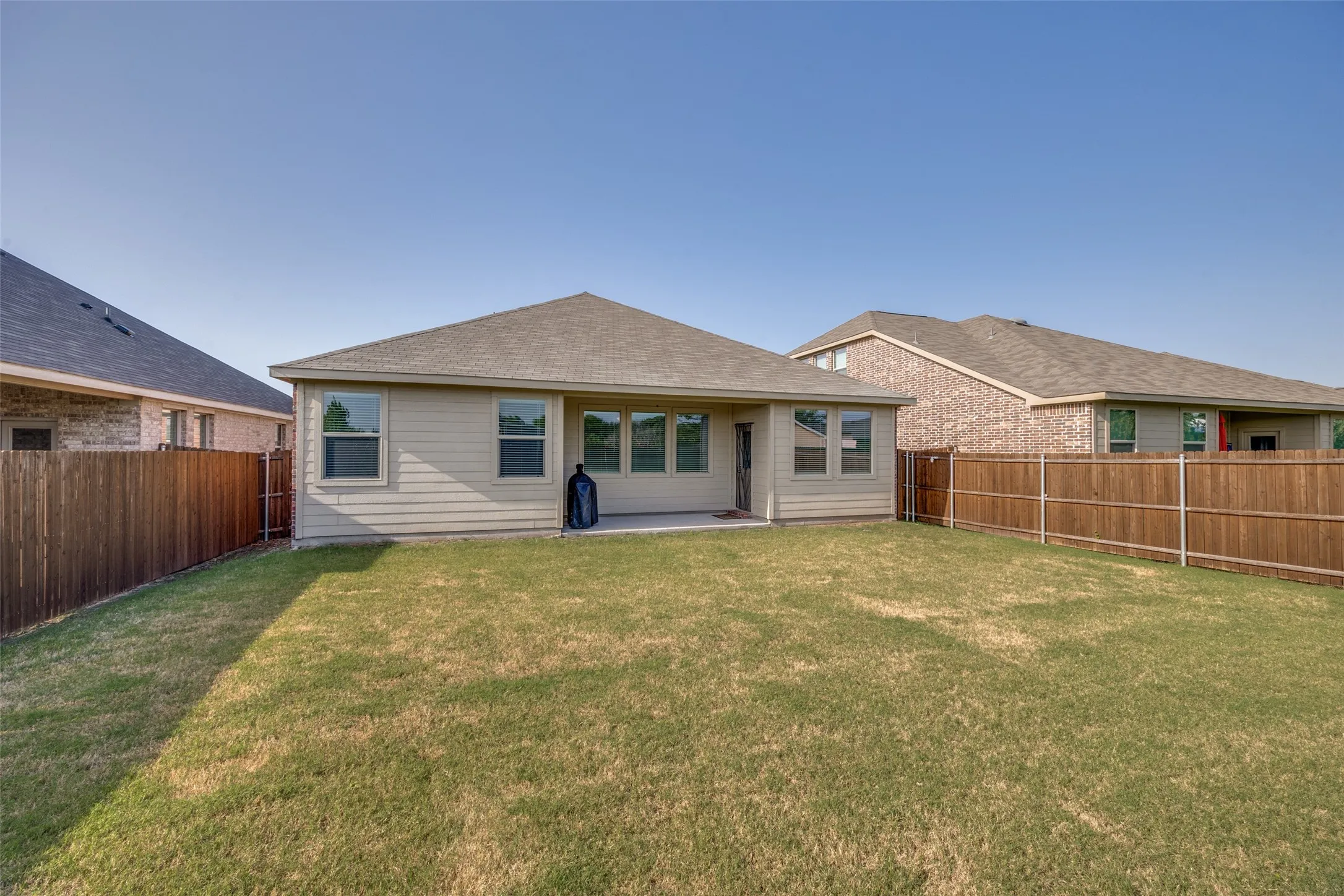 Expansive backyard featuring a manicured lawn, full wood fencing, and a concrete patio