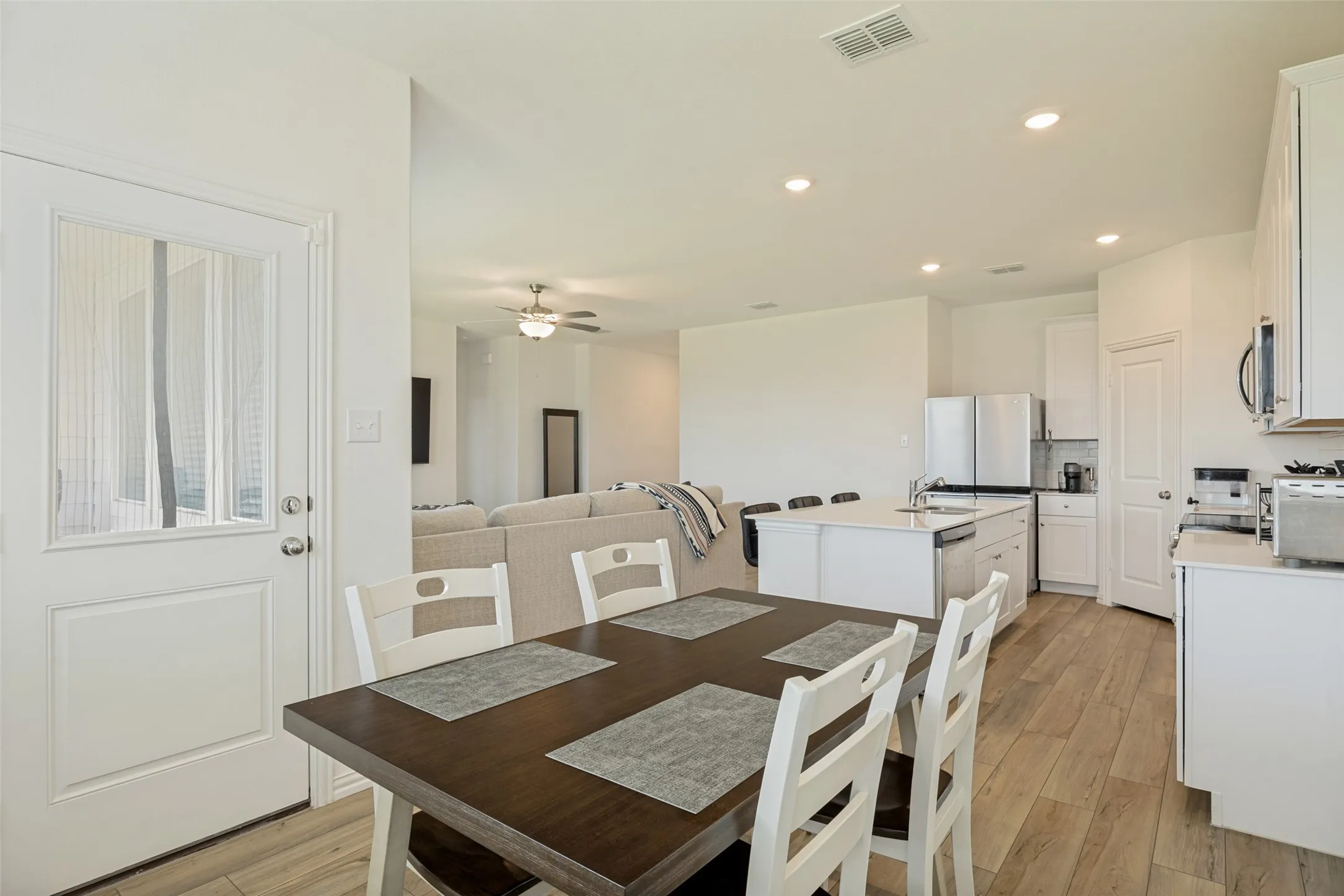 Open-concept living area featuring wood-finish flooring, recessed lighting, and a kitchen island with seating