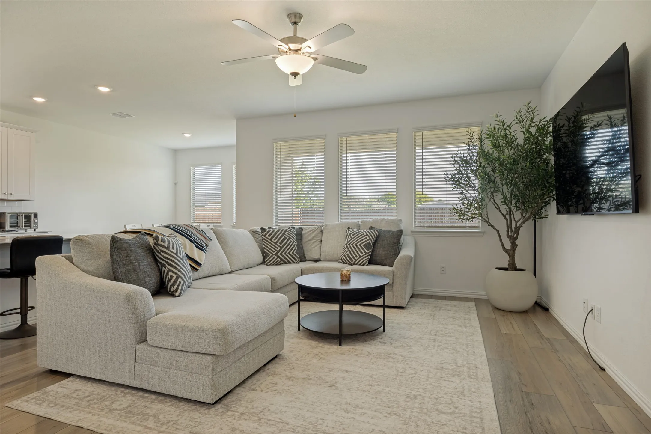 Open-concept living space featuring wood-finish flooring, recessed lighting, and a ceiling fan