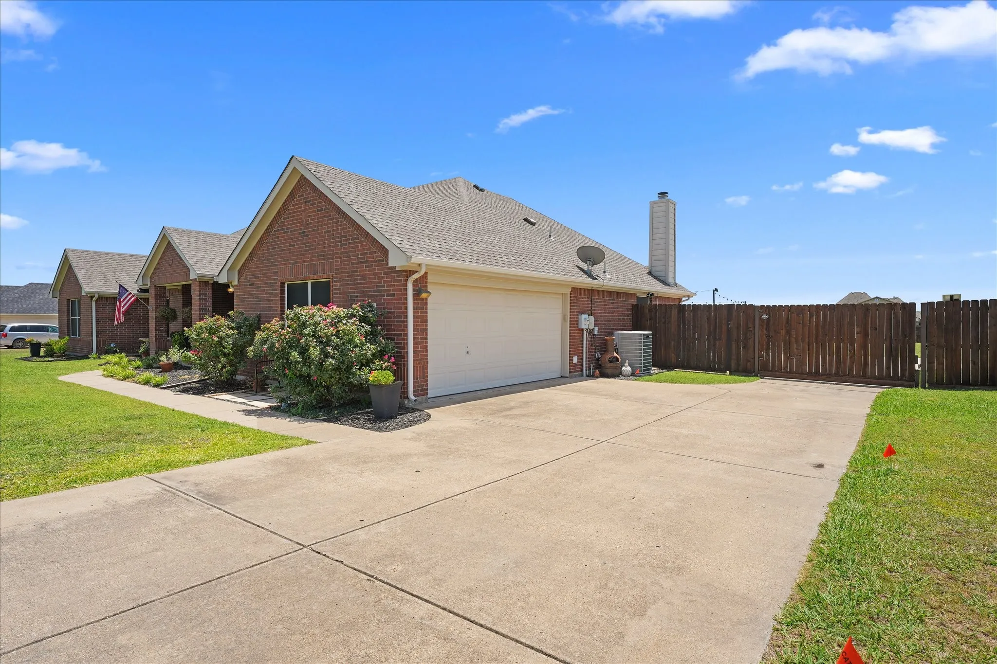Brick exterior with an attached side entry garage, concrete driveway, and a wood privacy fence