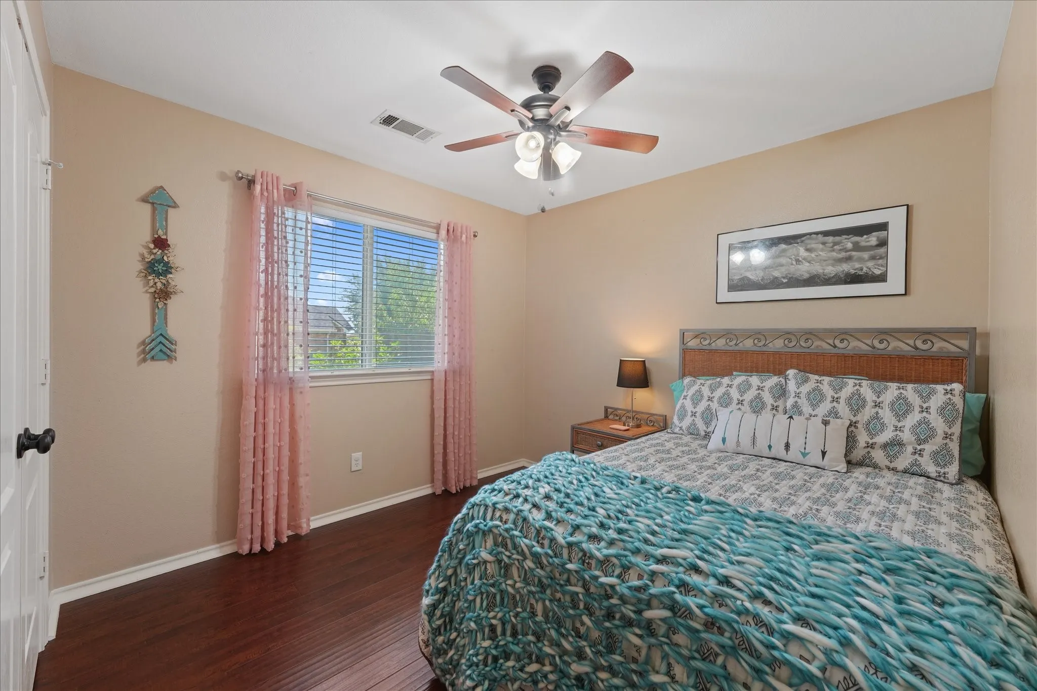 Bedroom featuring wood-finish flooring, a ceiling fan with integrated lighting, and a window with blinds
