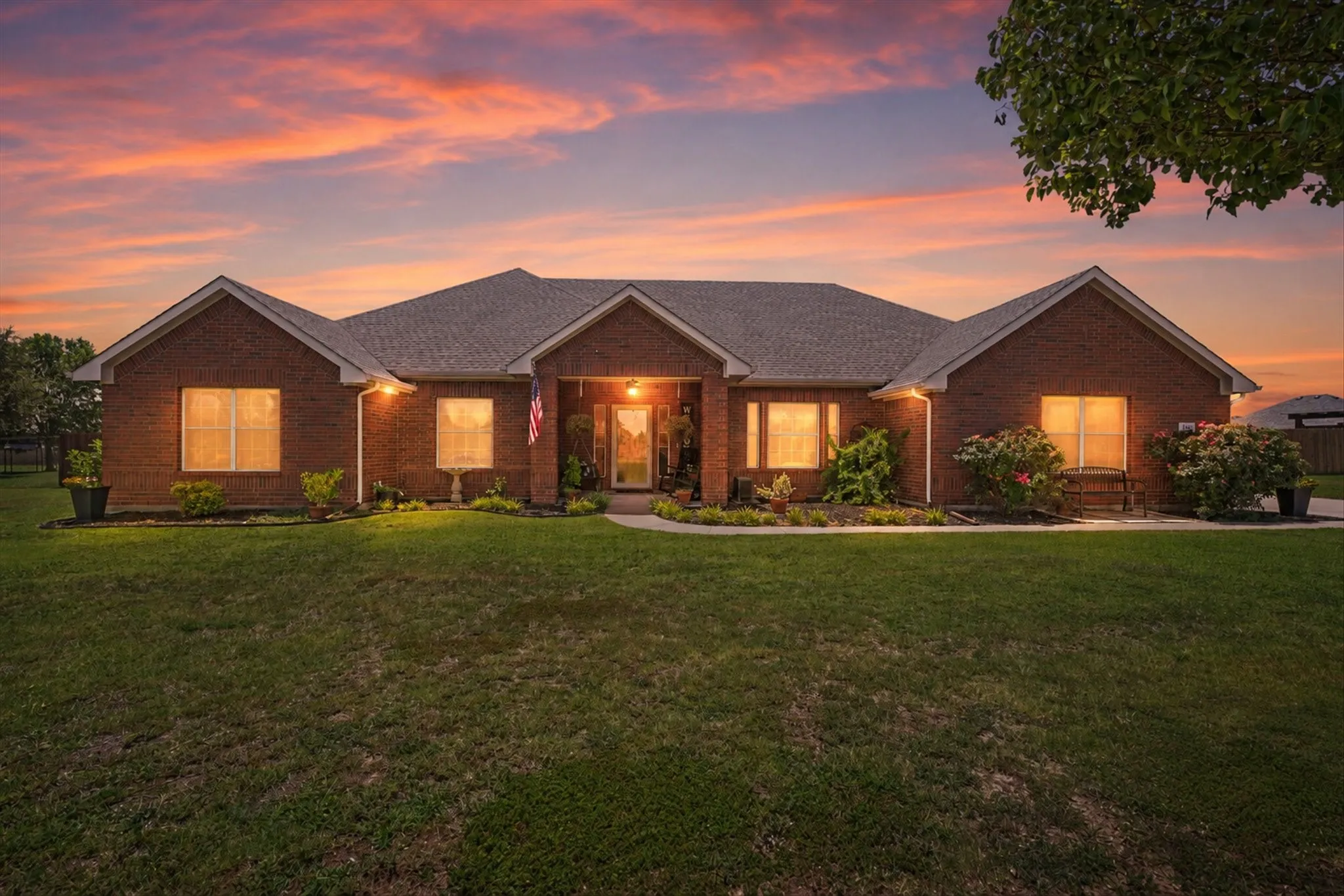 Brick exterior with covered front porch, gabled roofline and manicured front lawn