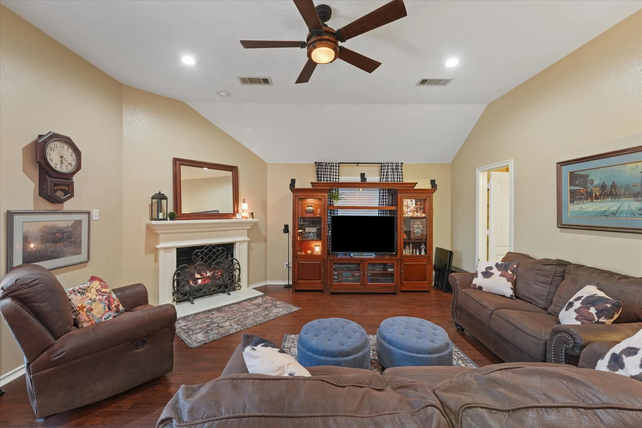 Living area featuring a vaulted ceiling with a ceiling fan, recessed lighting, wood-finish flooring and a fireplace with a decorative white mantel