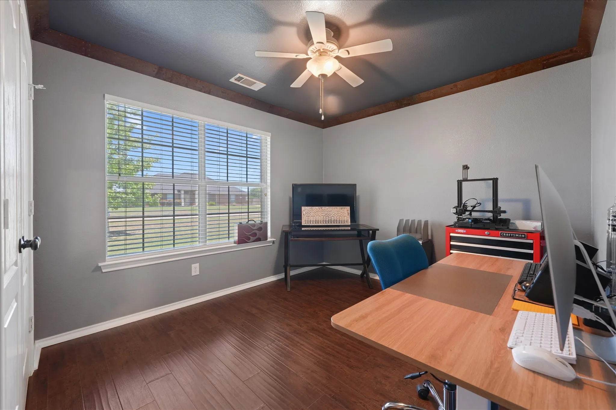 Bedroom being used as an office space with wood finish flooring and a contemporary ceiling fan