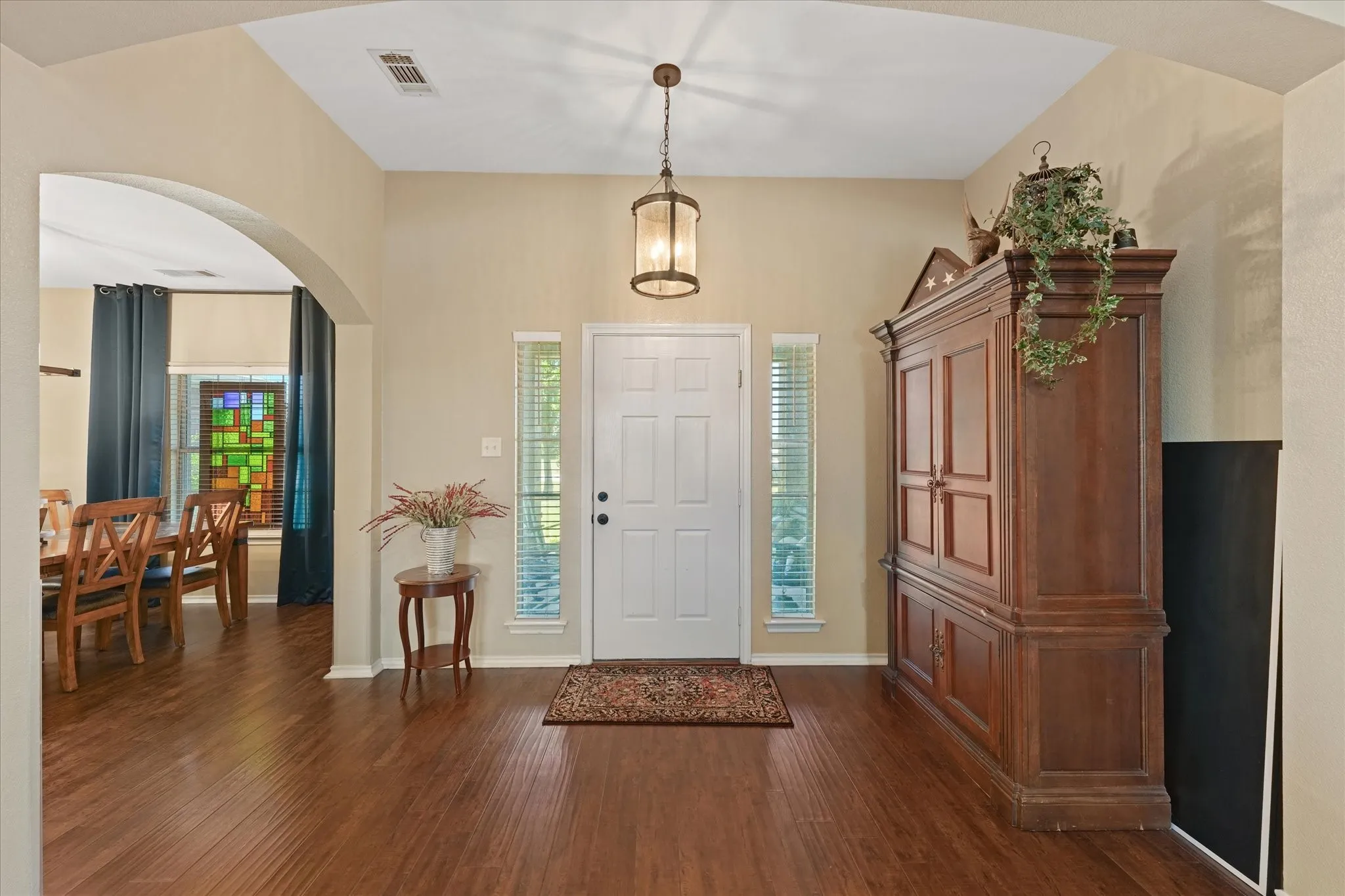 Entryway featuring high ceilings, wood-finish flooring, and an arched opening leading to the formal dining room