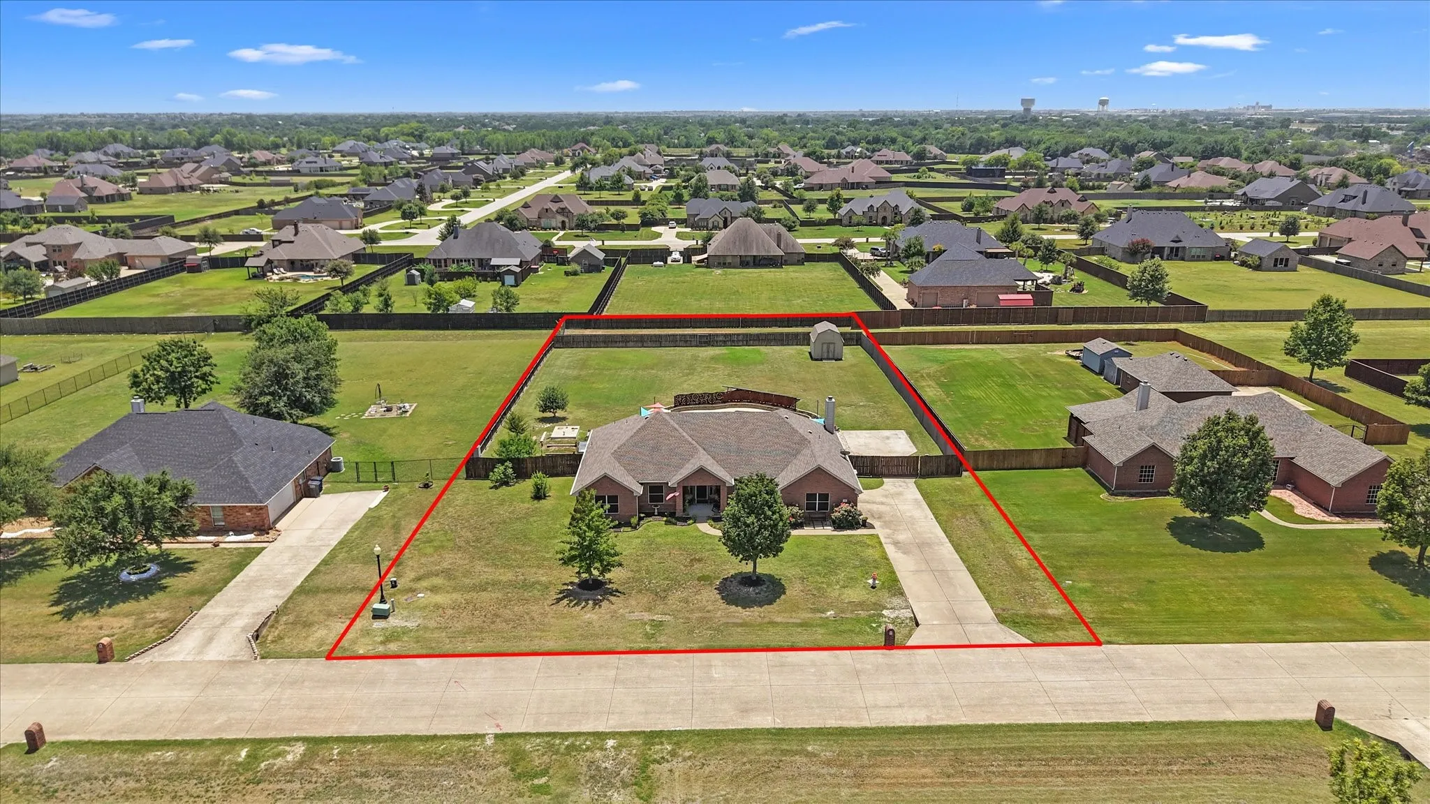 Expansive property featuring a single-story brick residence with a gabled roofline, a detached garage, and a large, fenced backyard