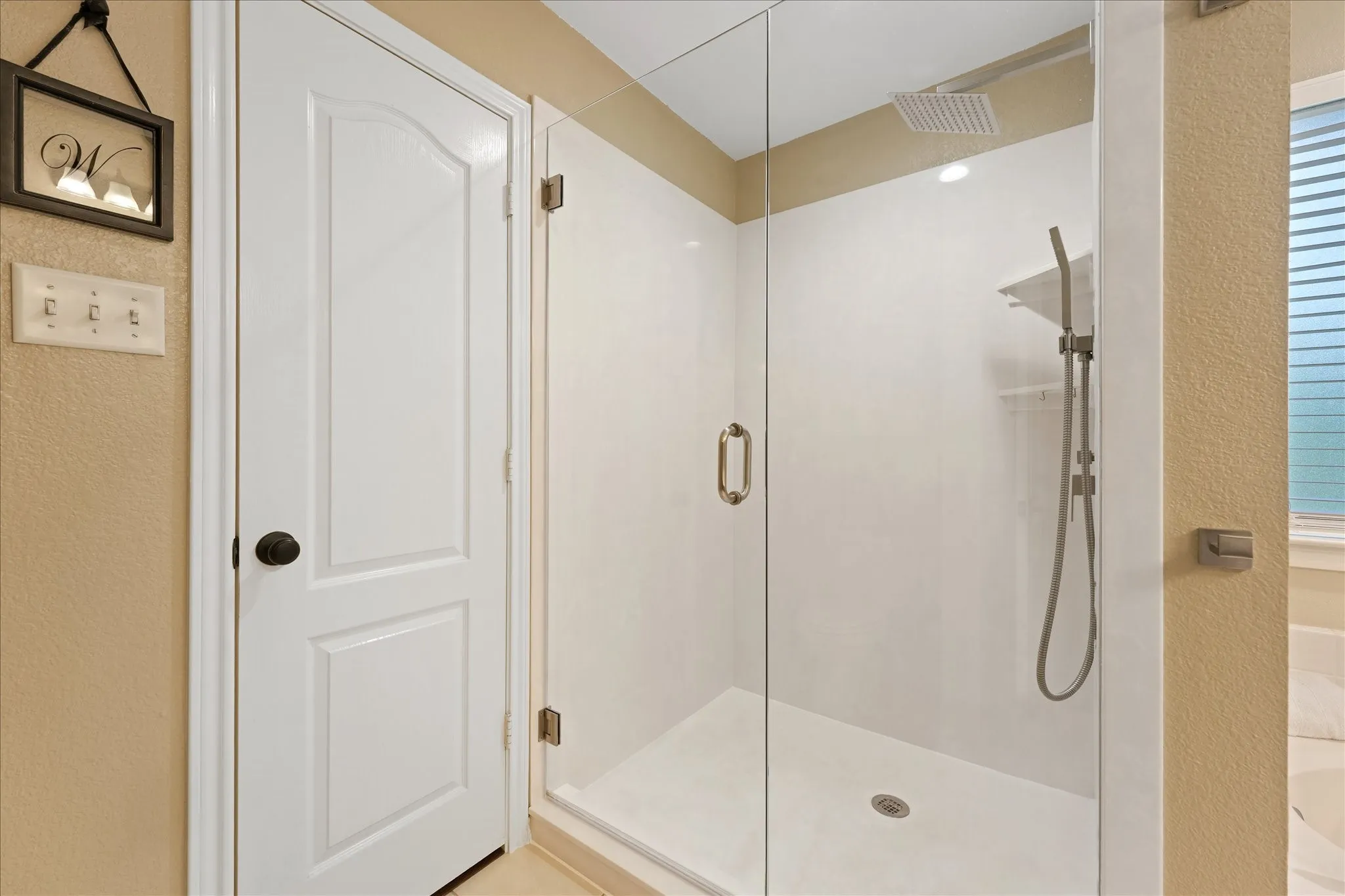 Glass-enclosed shower featuring a rainfall showerhead, handheld shower fixture, and recessed lighting