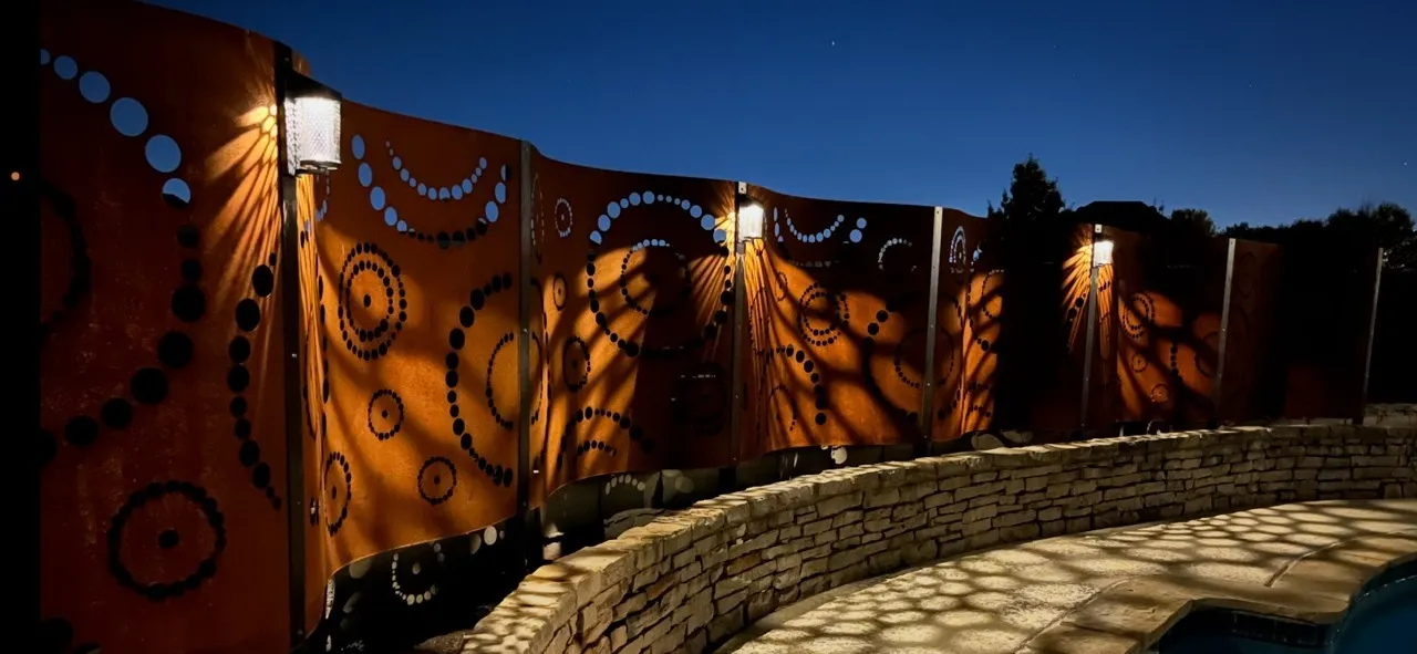 Beautiful, custom art deco steel privacy wall with decorative lighting at twilight