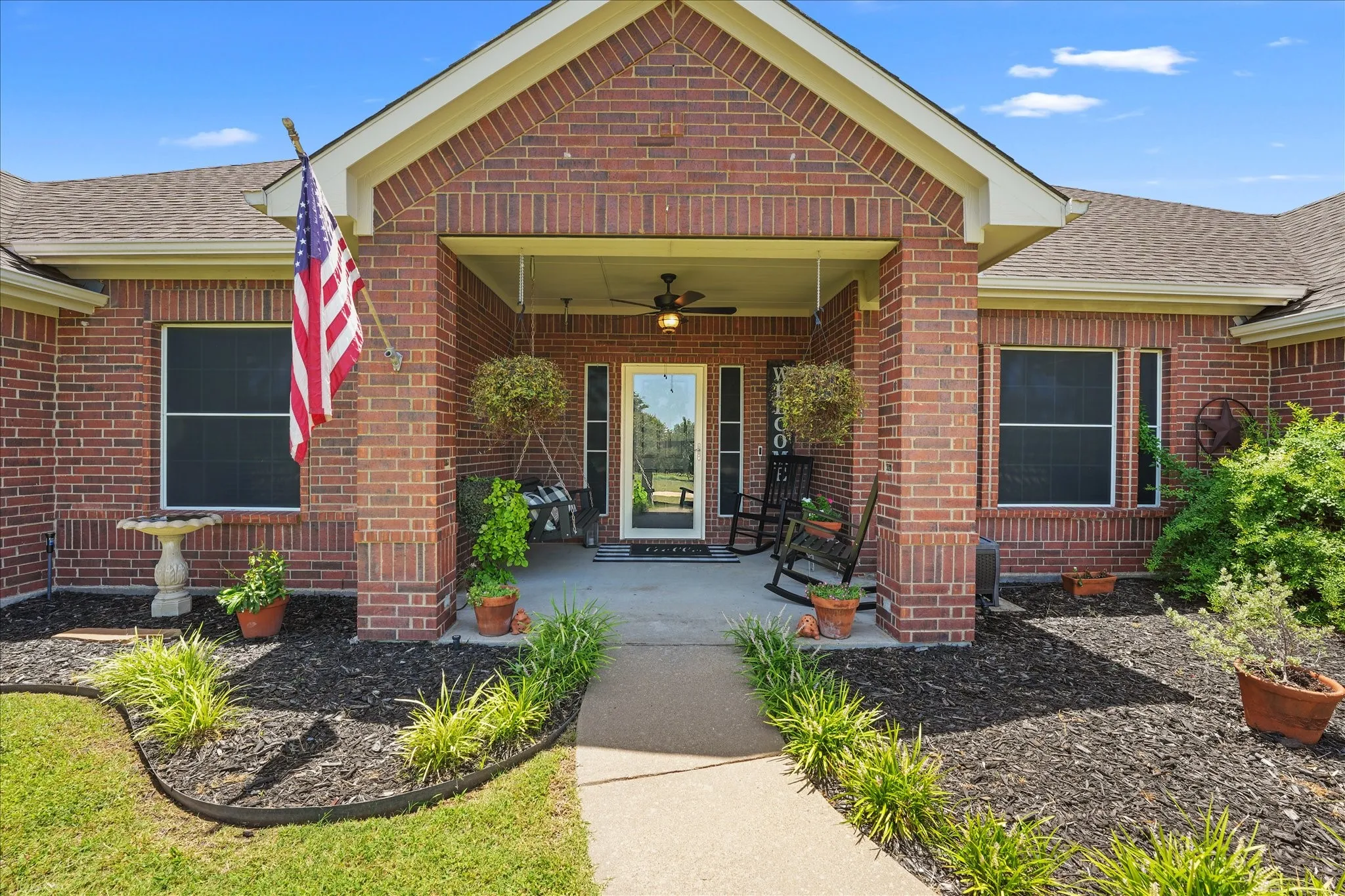 Brick exterior featuring a covered front porch with a ceiling fan