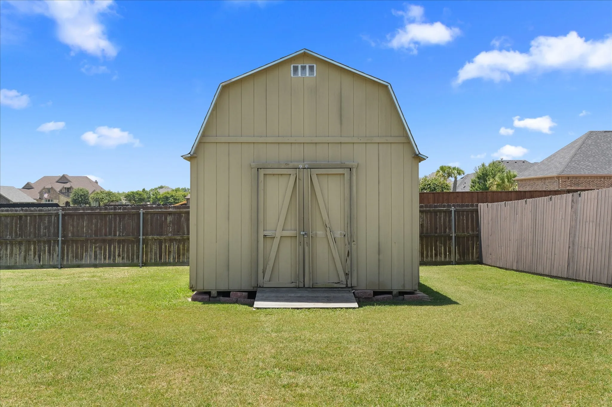 Gable-roofed outdoor storage building featuring double wooden doors and a small gable vent