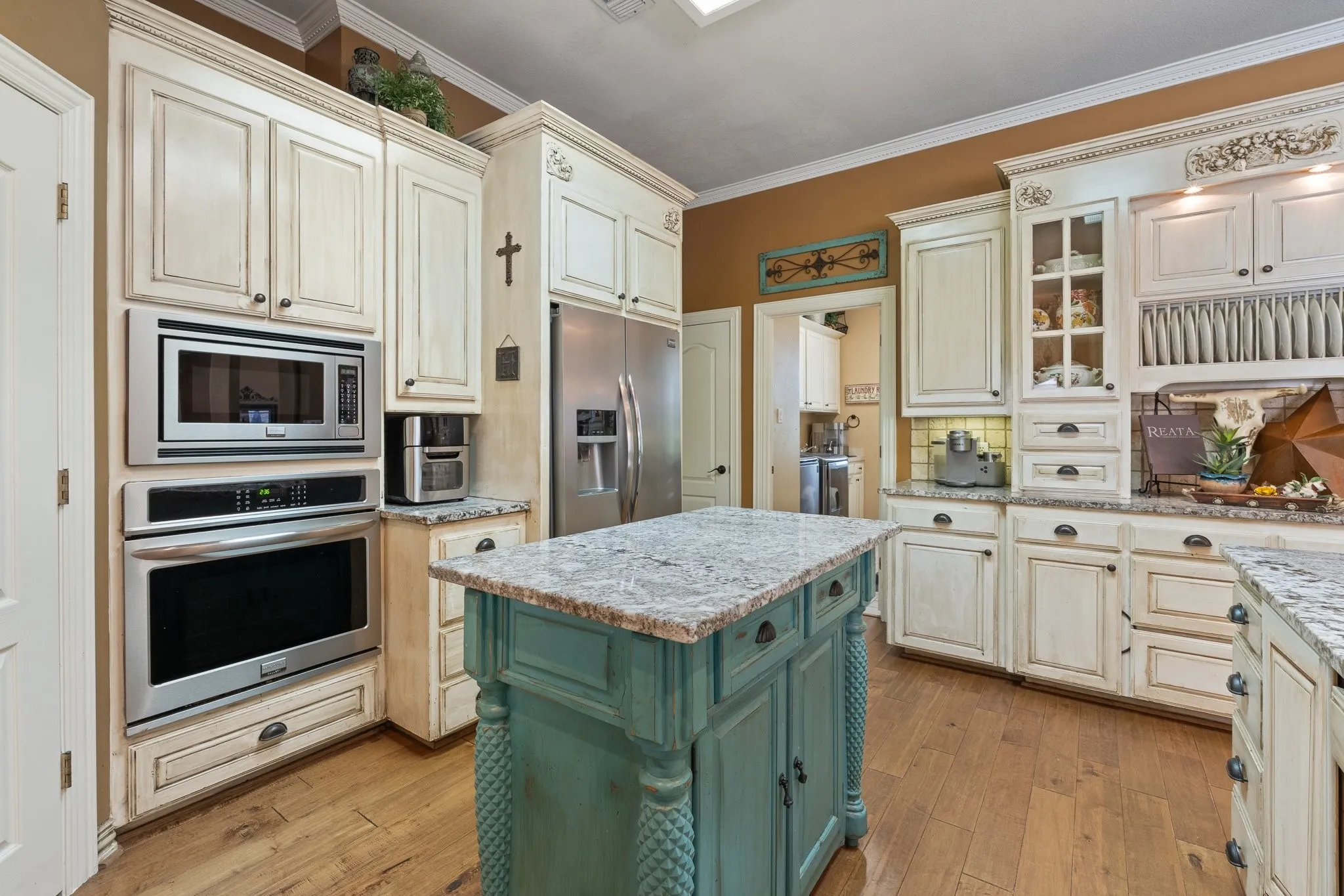 Kitchen featuring a central island with a granite countertop, wood-finish flooring, custom cabinetry, stainless steel built-in appliances, and recessed lighting
