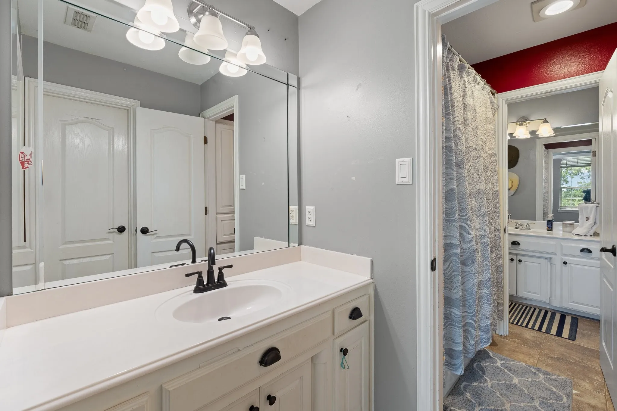 Jack and Jill Bathroom with vanity featuring an integrated sink, matte black faucet, and white cabinetry with dark hardware