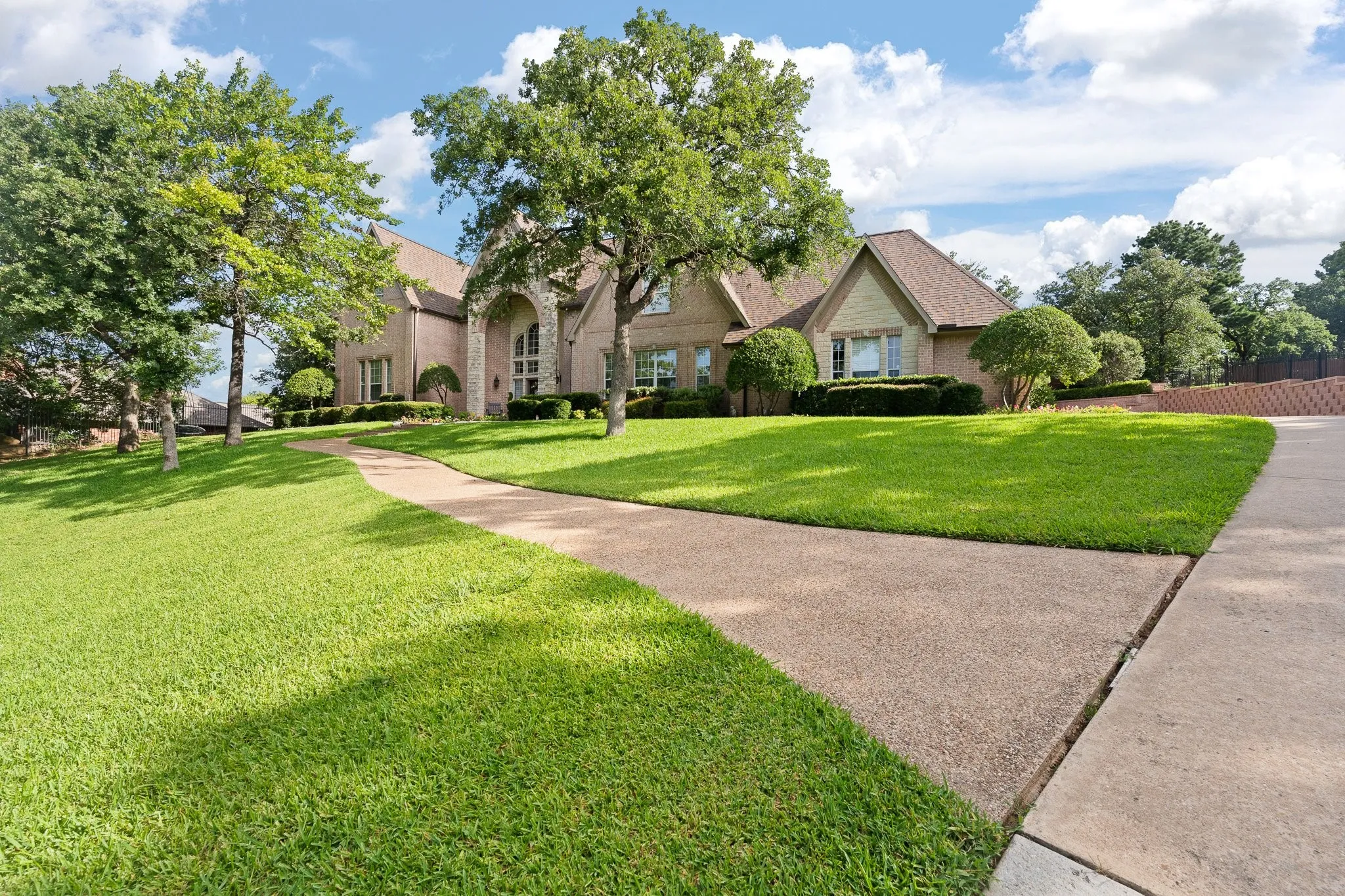Exterior front view featuring a lovely sidewalk leading to a brick and stone entry with arches and architectural gables
