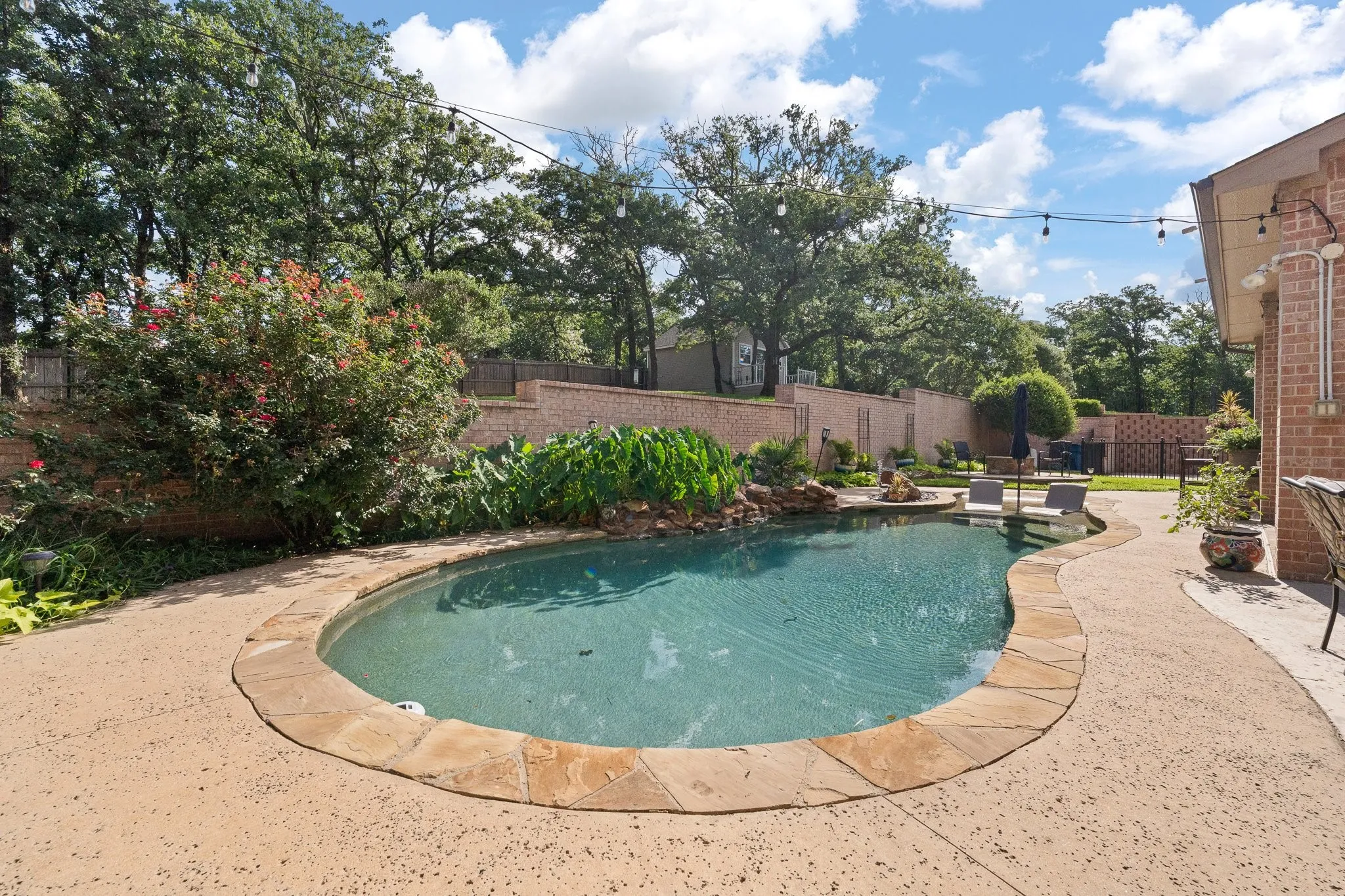 Freeform swimming pool with natural stone coping and a rock waterfall feature