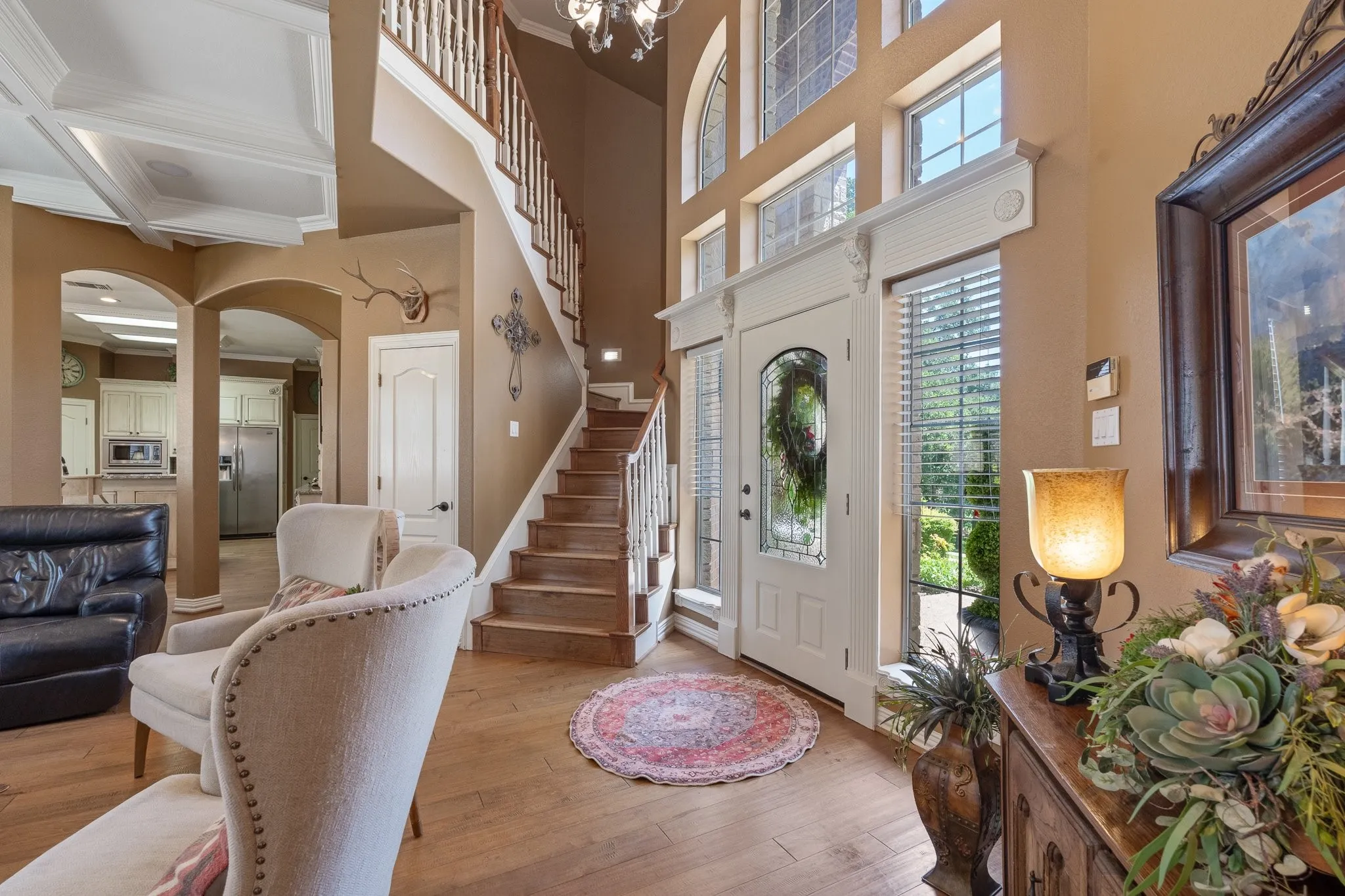 Grand entryway featuring a custom wood staircase, wood-finish flooring, a decorative front door with side panel windows, and arched​​‌​​​​‌​​‌‌​‌‌​​​‌‌​‌​‌​‌​​​‌​​ doorways