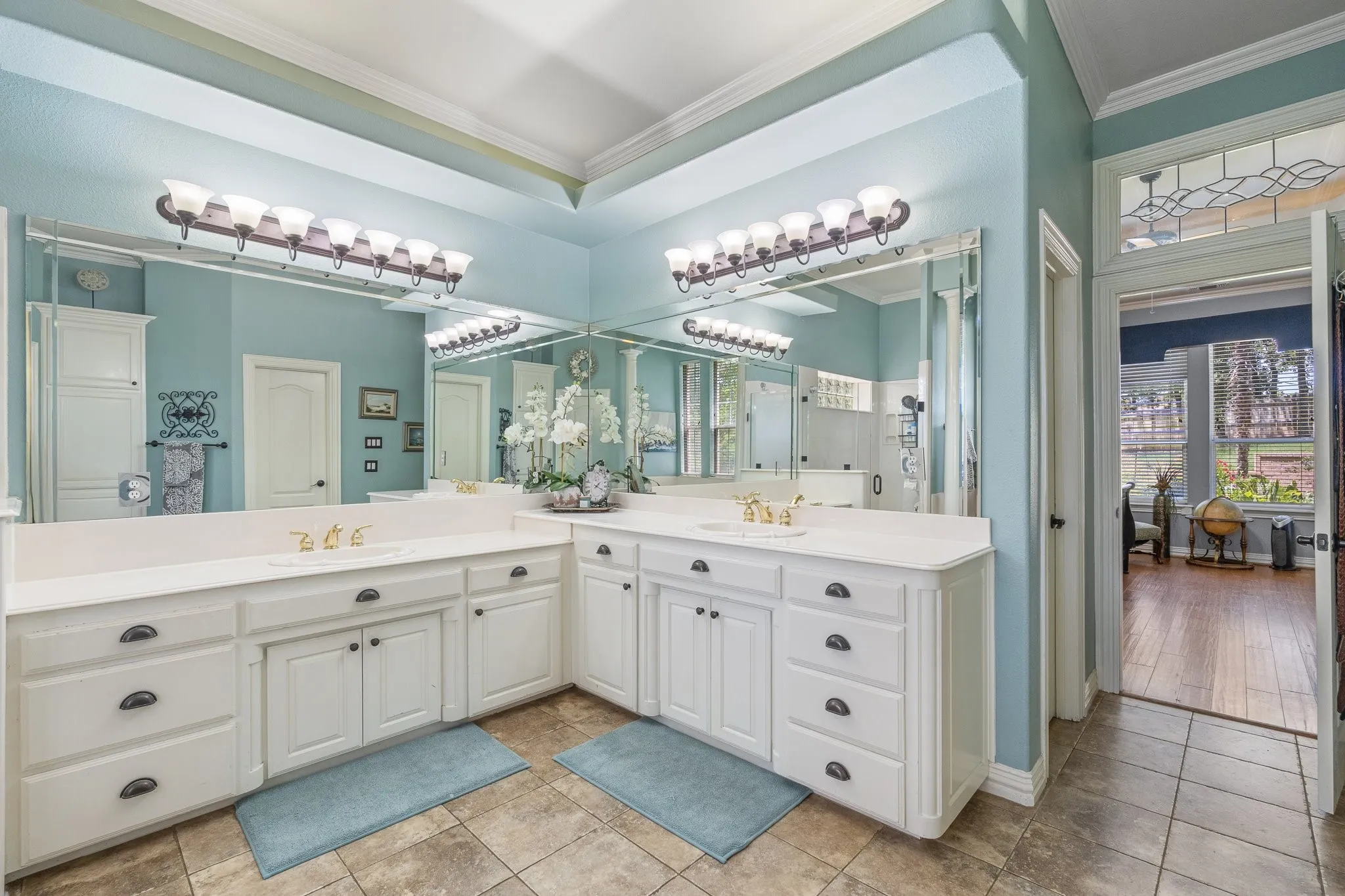 Double vanity featuring white cabinetry, integrated sinks, white countertops, and full-wall mirrors