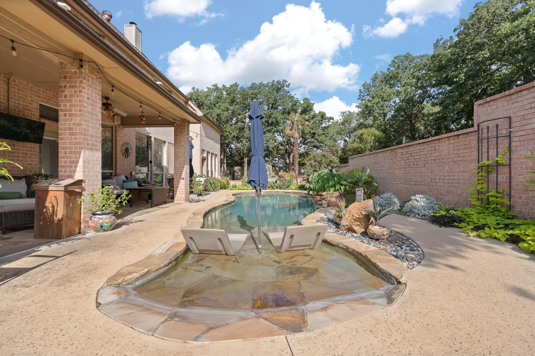 Custom-shaped swimming pool featuring a tanning ledge with two submerged loungers