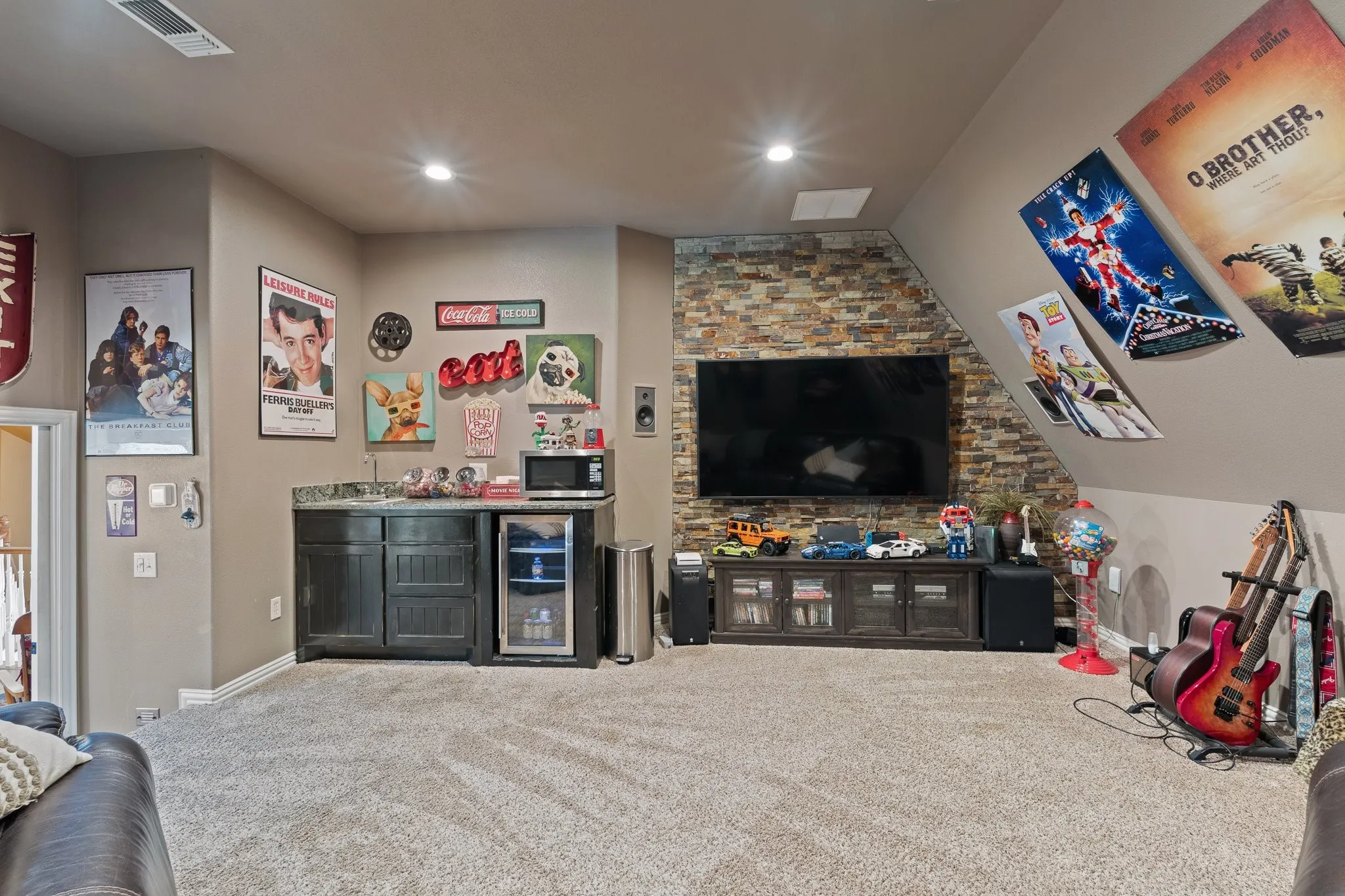 Entertainment space featuring a stacked stone accent wall, recessed lighting, and a built-in wet bar with dark cabinetry