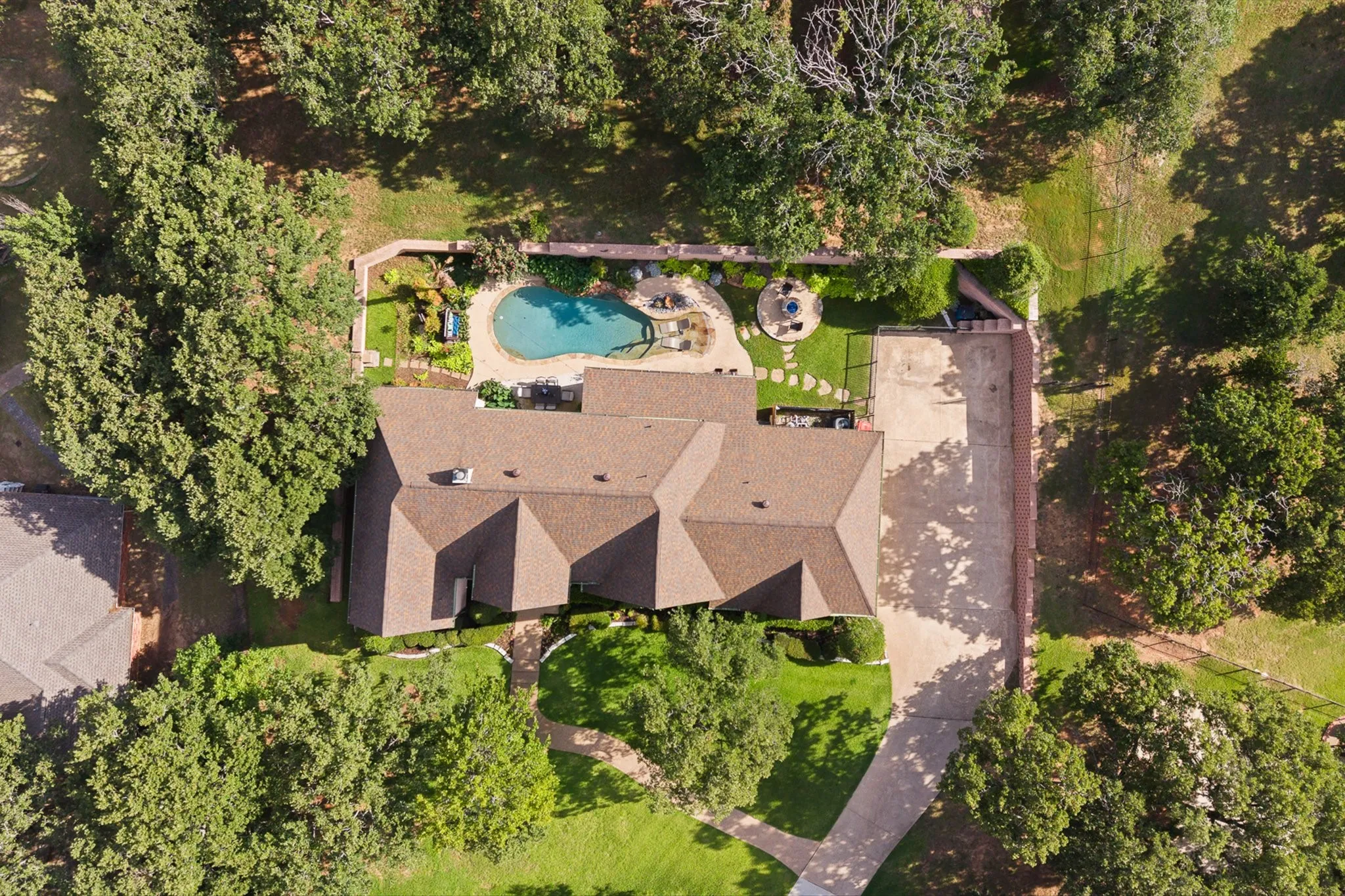 Expansive property featuring a multi-gabled roofline, private swimming pool, stone patio, and mature trees