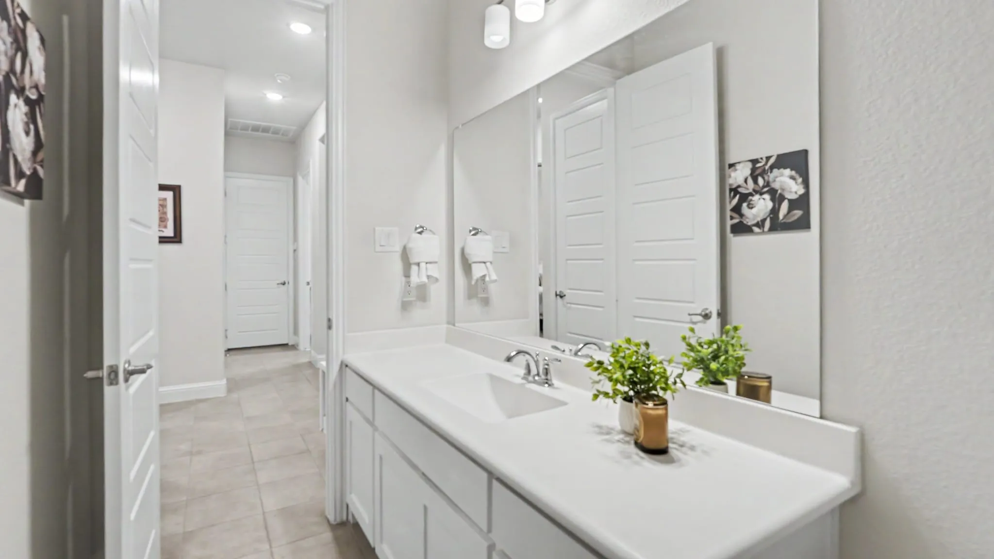 Dual vanity with integrated sinks, chrome fixtures, and an large mirror. Located in hallway near two bedrooms, making this a great layout for multi-gen living.