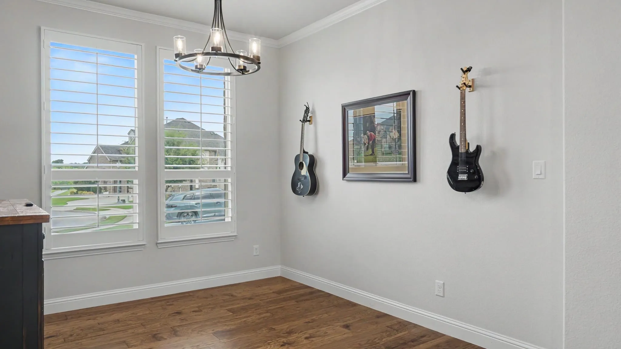 Formal dining/bar/sitting area with custom shiplap wall and industrial farmhouse style shelves, showcasing hardwood floors and plantation shutters that overlook cul de sac. Could easily be converted to an enclosed room or office.