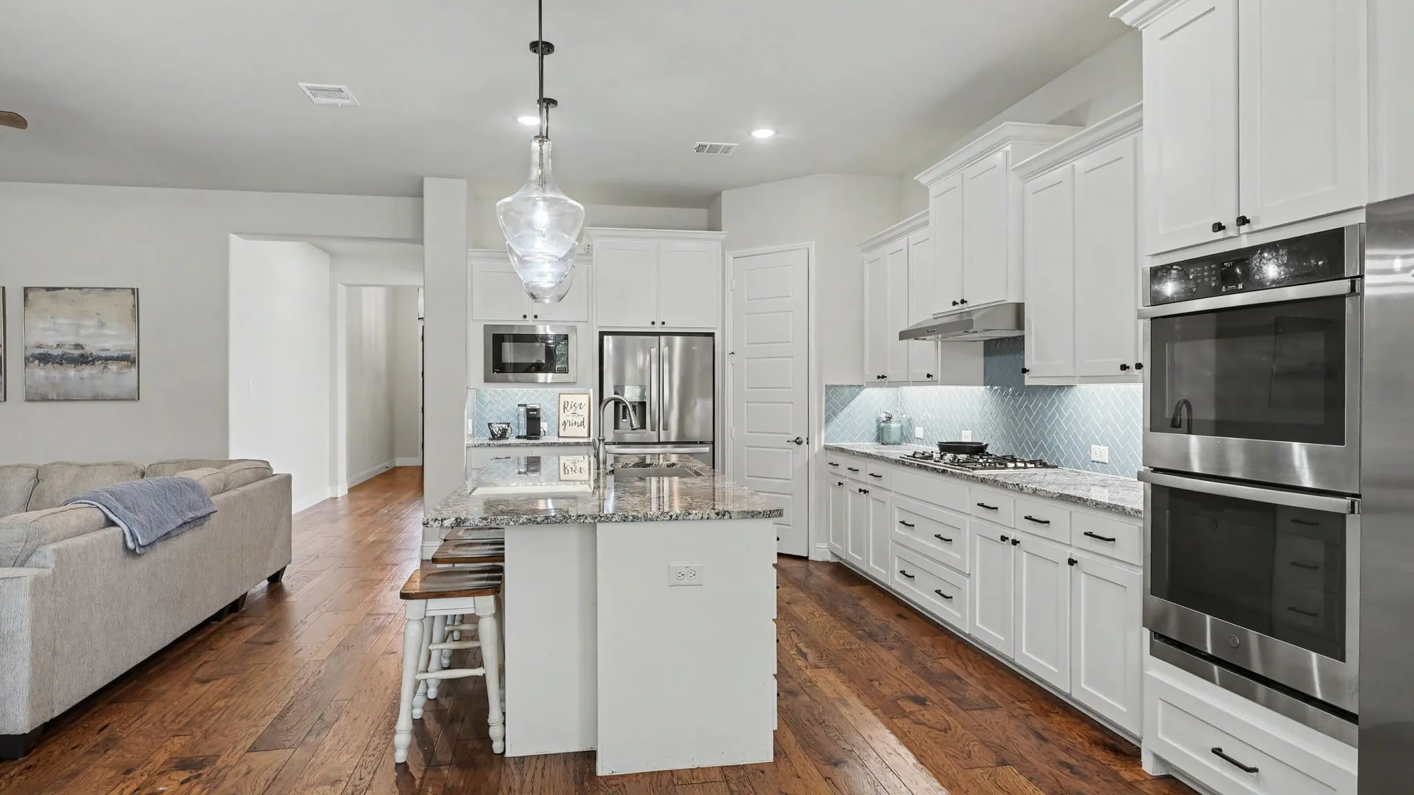 Gourmet kitchen featuring white cabinetry, stainless steel appliances, a center island with countertop seating, and hardwood floors.