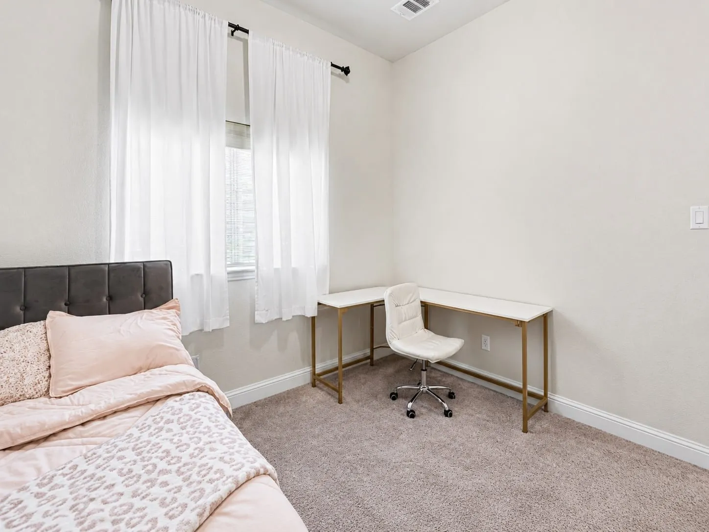 Carpeted room featuring light-toned walls and a window with white bamboo blinds. Features a walk-in closet.