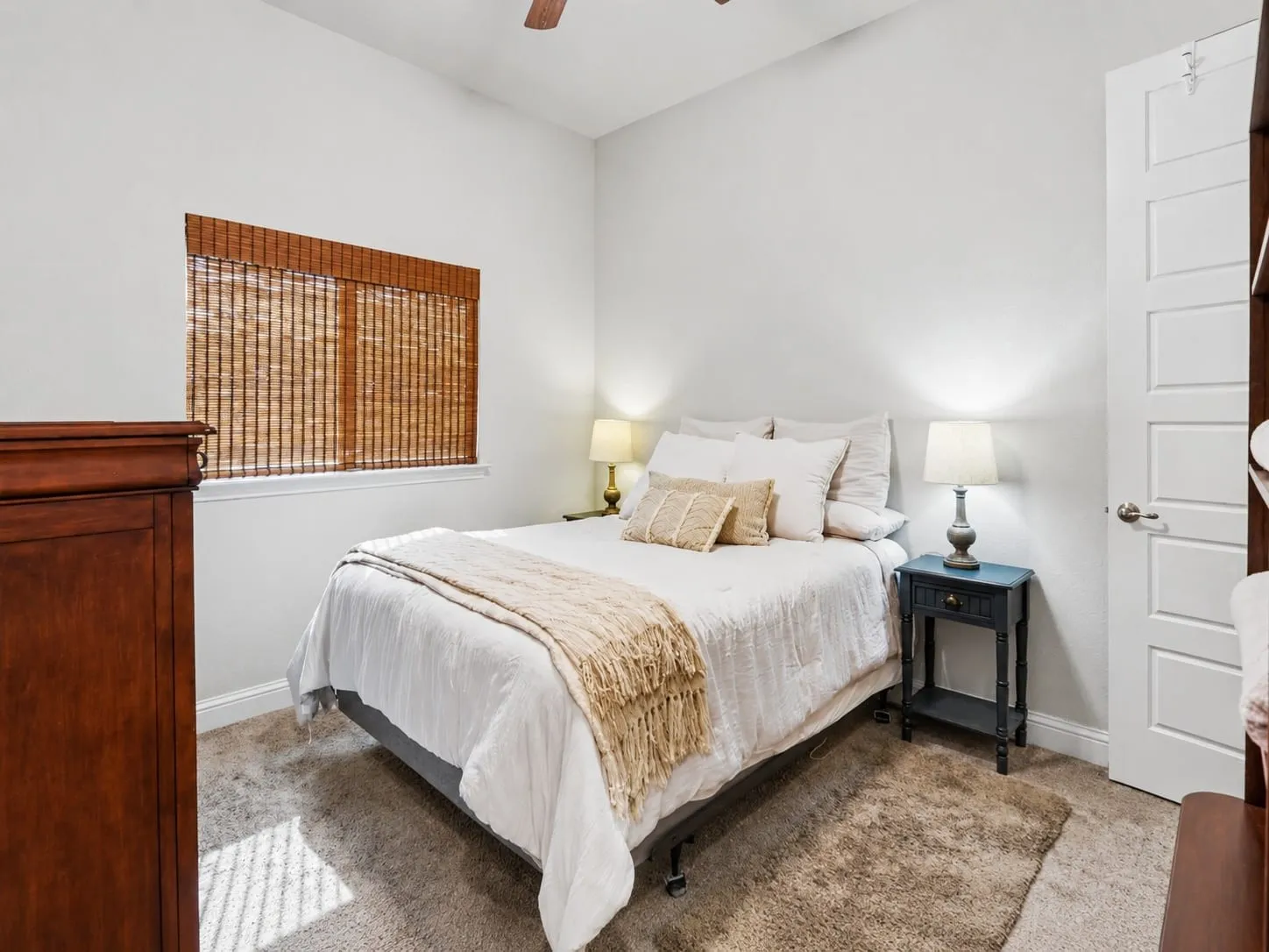 Carpeted room featuring a window with woven bamboo blinds, a ceiling fan, and a paneled interior door. Large closet.