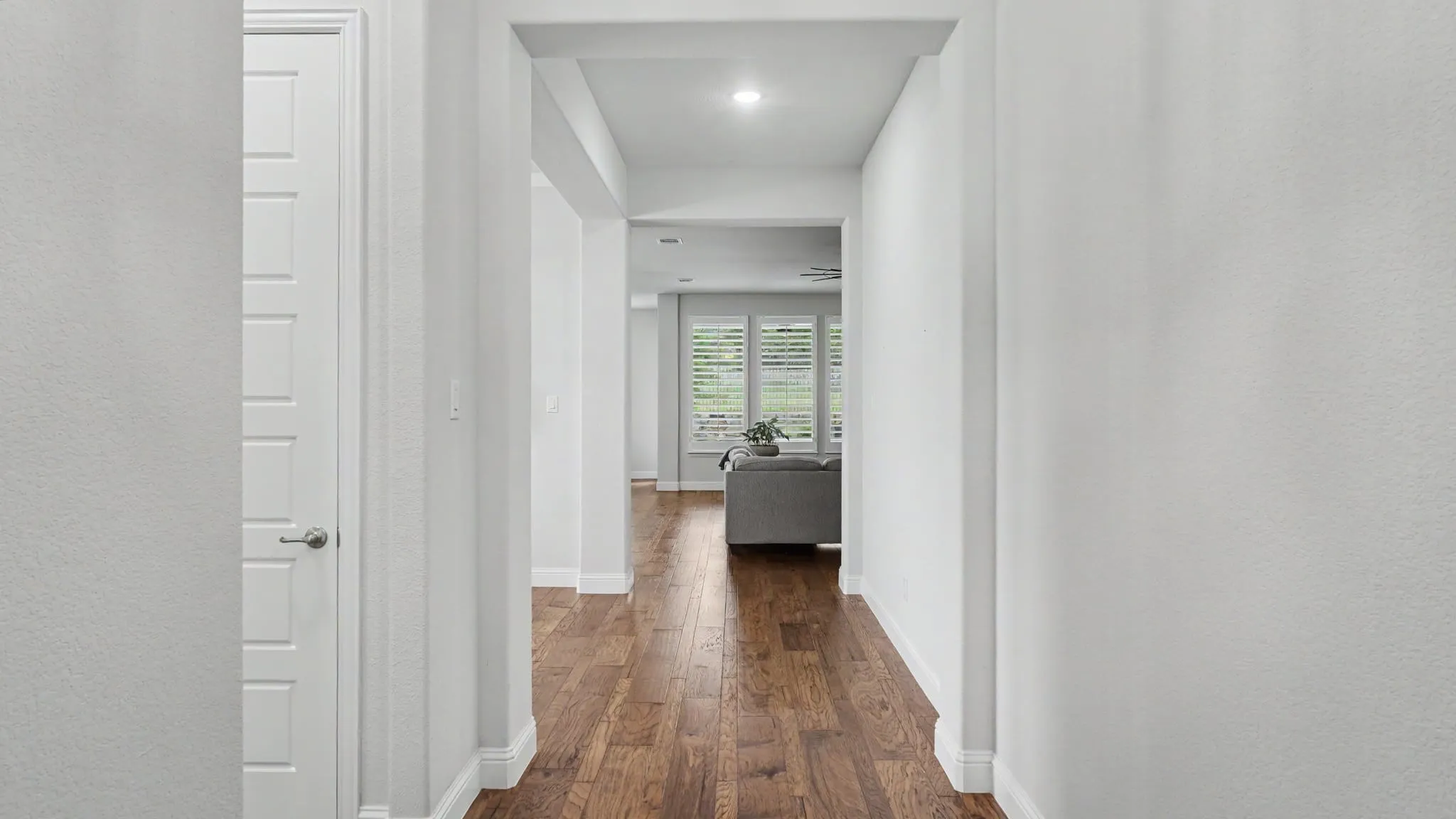Entry hallway featuring hardwood floors looking through to the living room, kitchen and backyard.