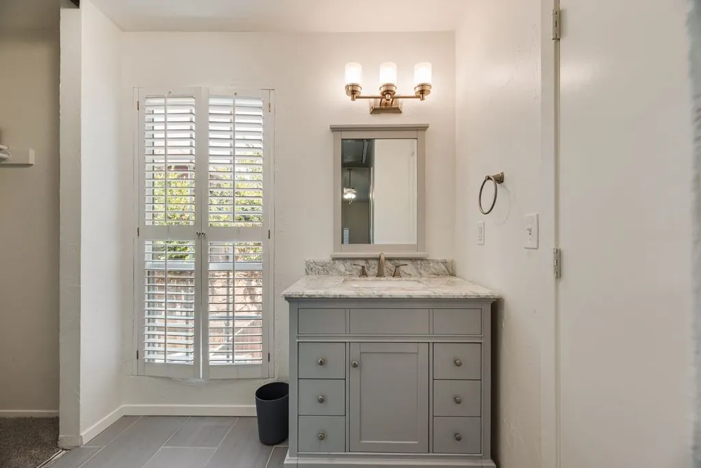 Bathroom featuring a gray vanity with stone countertop, undermount sink, and brushed nickel faucet