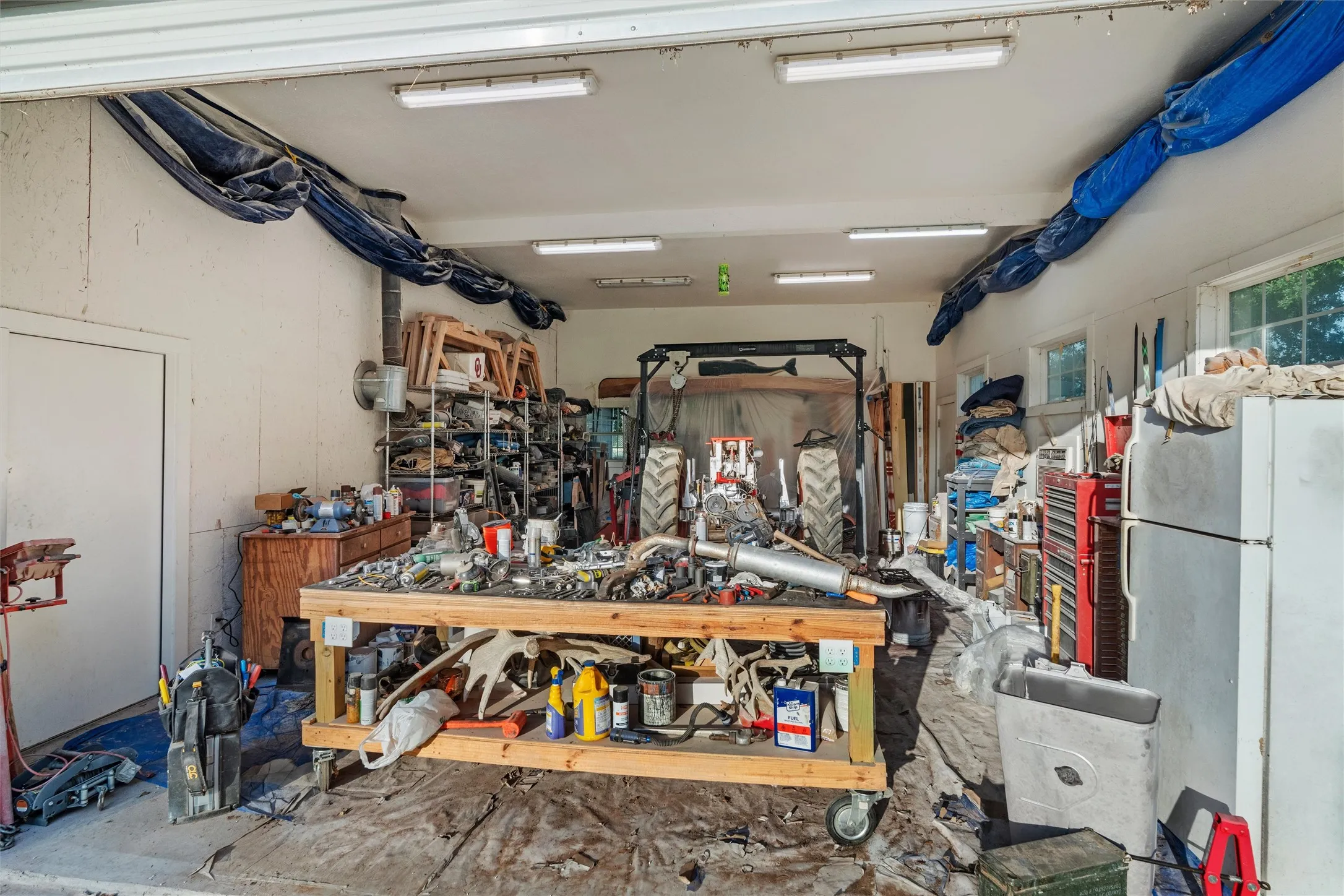 Spacious additional workshop space with multiple fluorescent lighting fixtures and a roll-up door.