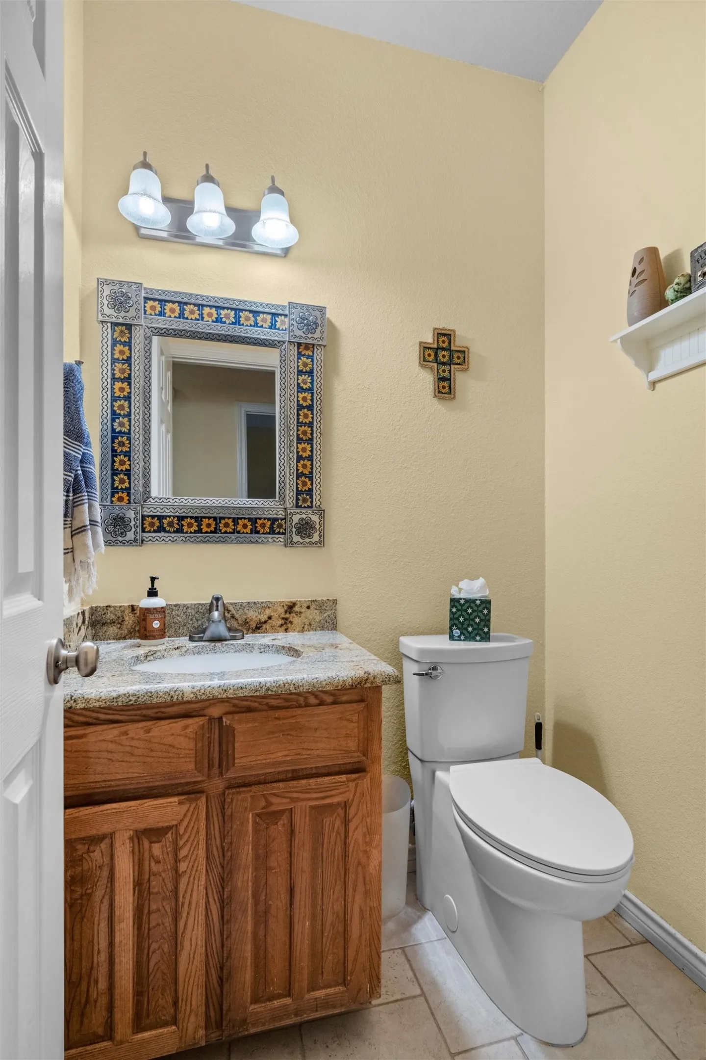 Powder room featuring a wood vanity with a granite-look countertop, undermount sink, and chrome-finish faucet