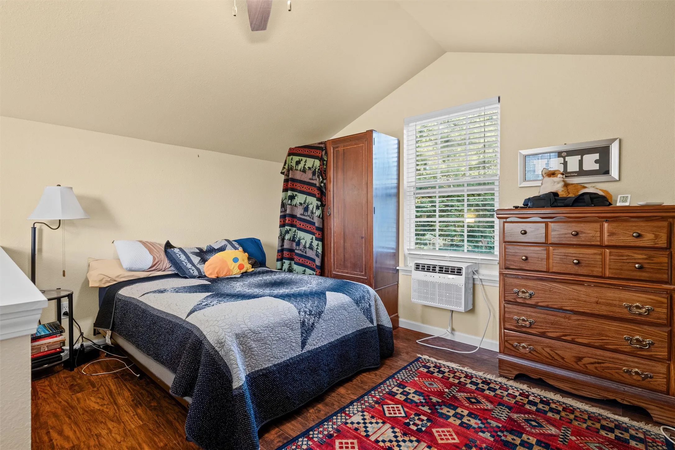 Room featuring wood-finish flooring, a window with horizontal blinds, and a sloped ceiling