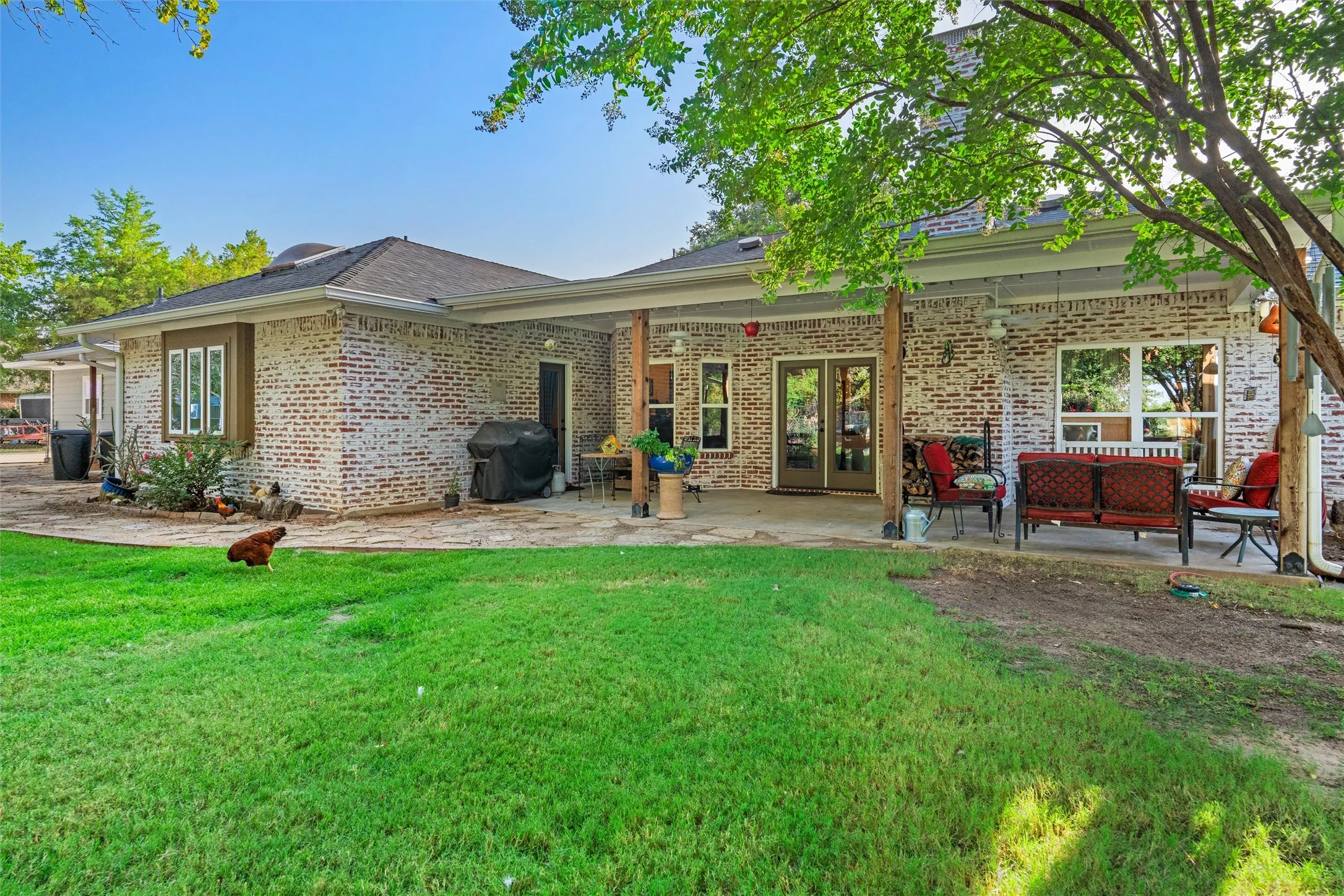 Expansive backyard with a manicured lawn, a full-length covered patio, and a stone paver patio