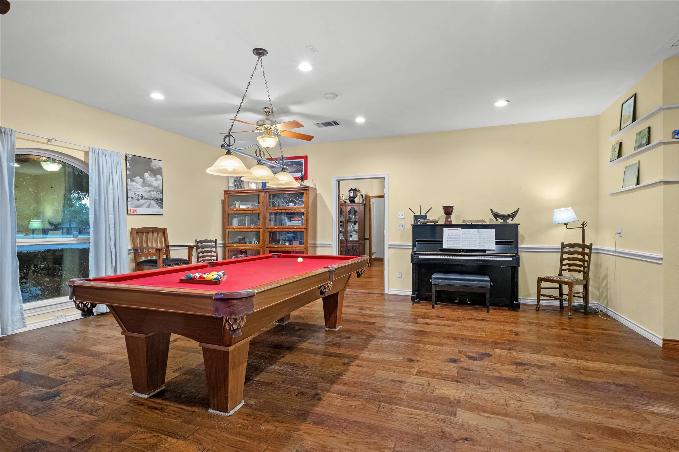 Spacious room featuring wood-finish flooring and light yellow walls with chair rail molding