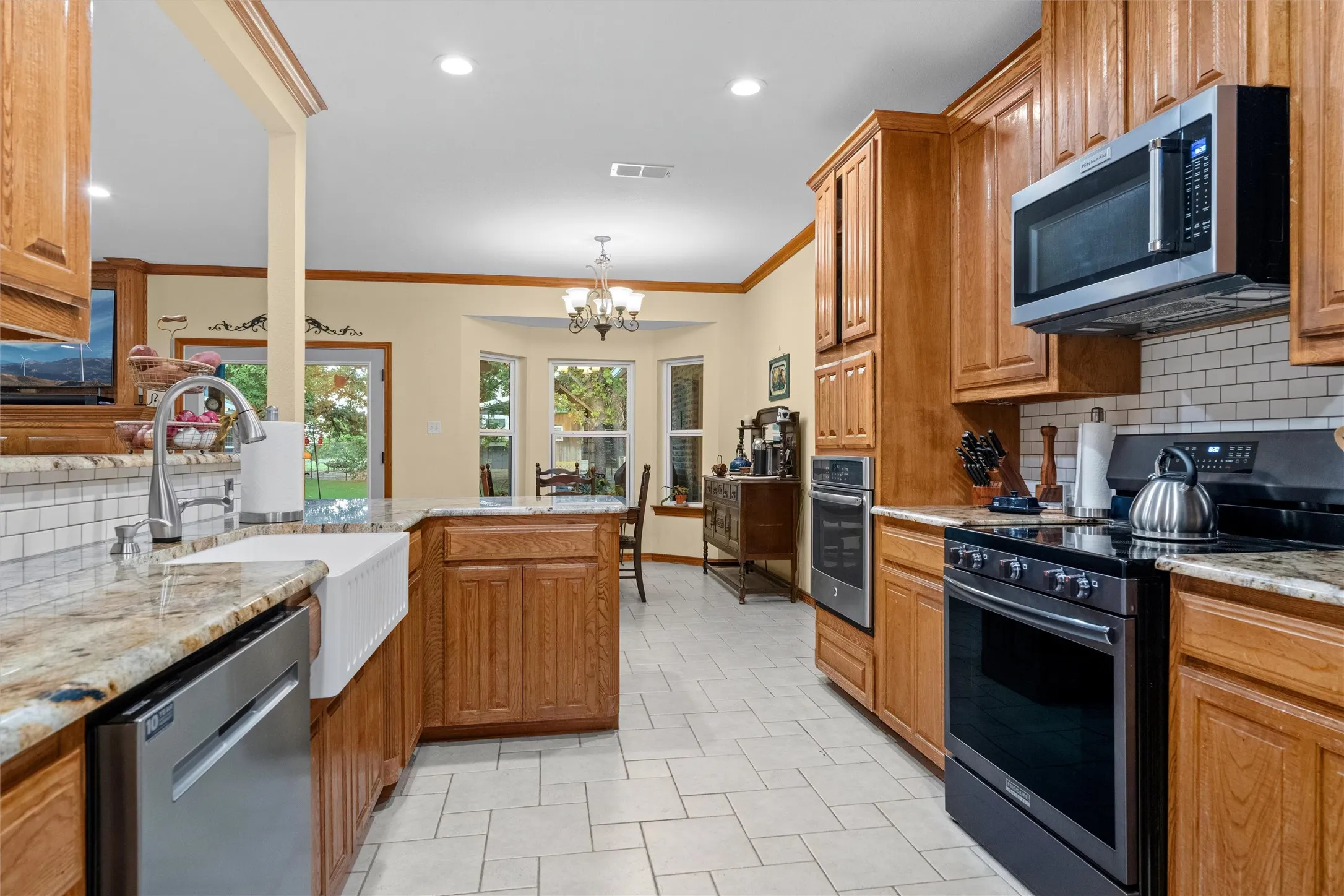 Kitchen featuring wood cabinetry, granite countertops, a white subway tile backsplash, stainless steel appliances, and tile flooring