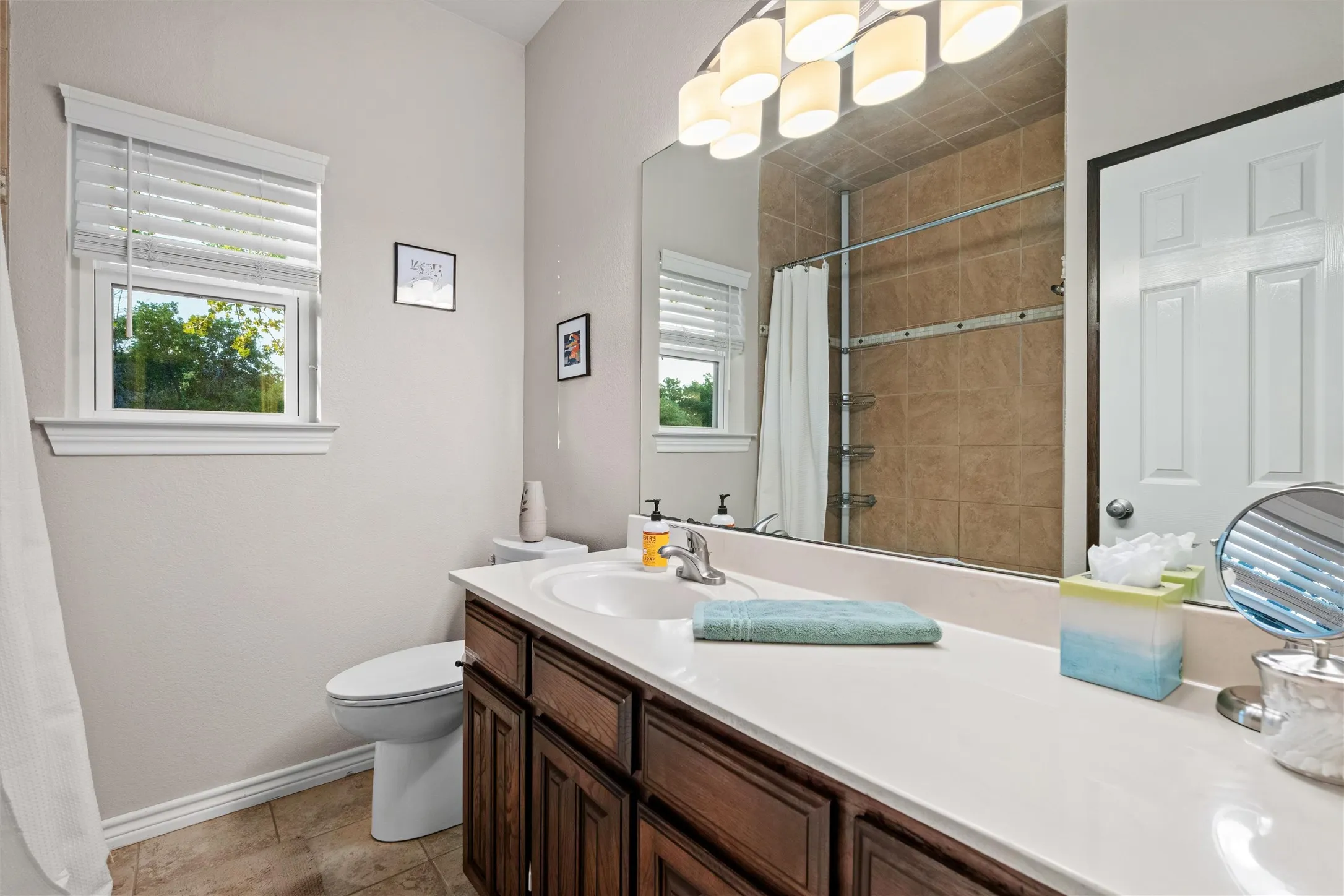 Bathroom featuring a single vanity with wood-finish cabinetry, a white countertop, and a large mirror