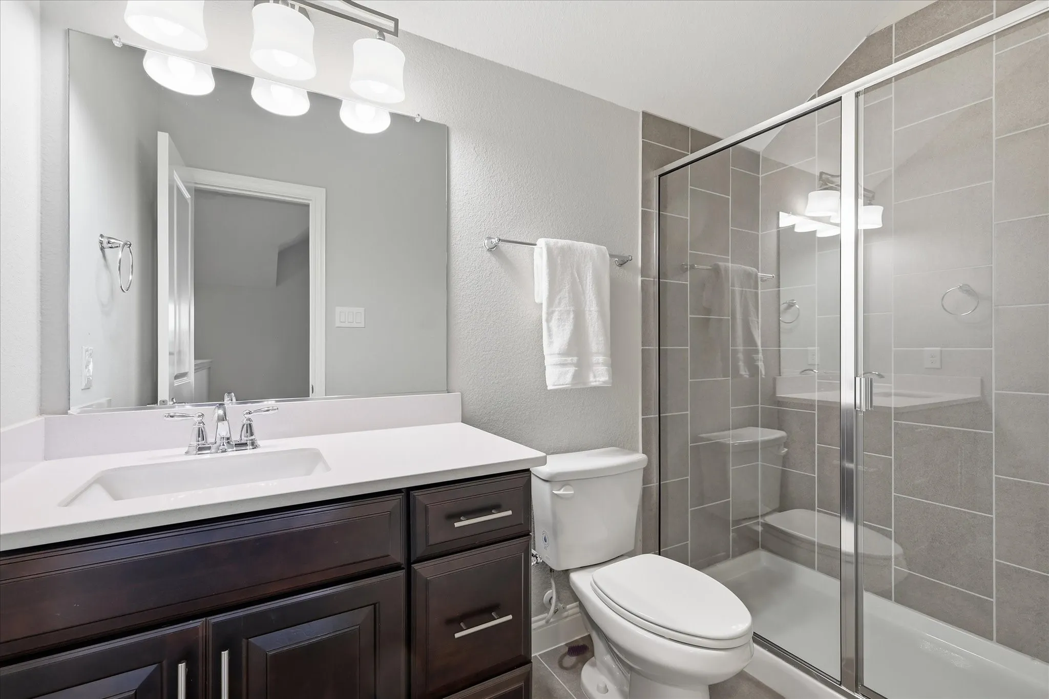 Bathroom with a dark wood-finish vanity, white countertop, and integrated rectangular sink