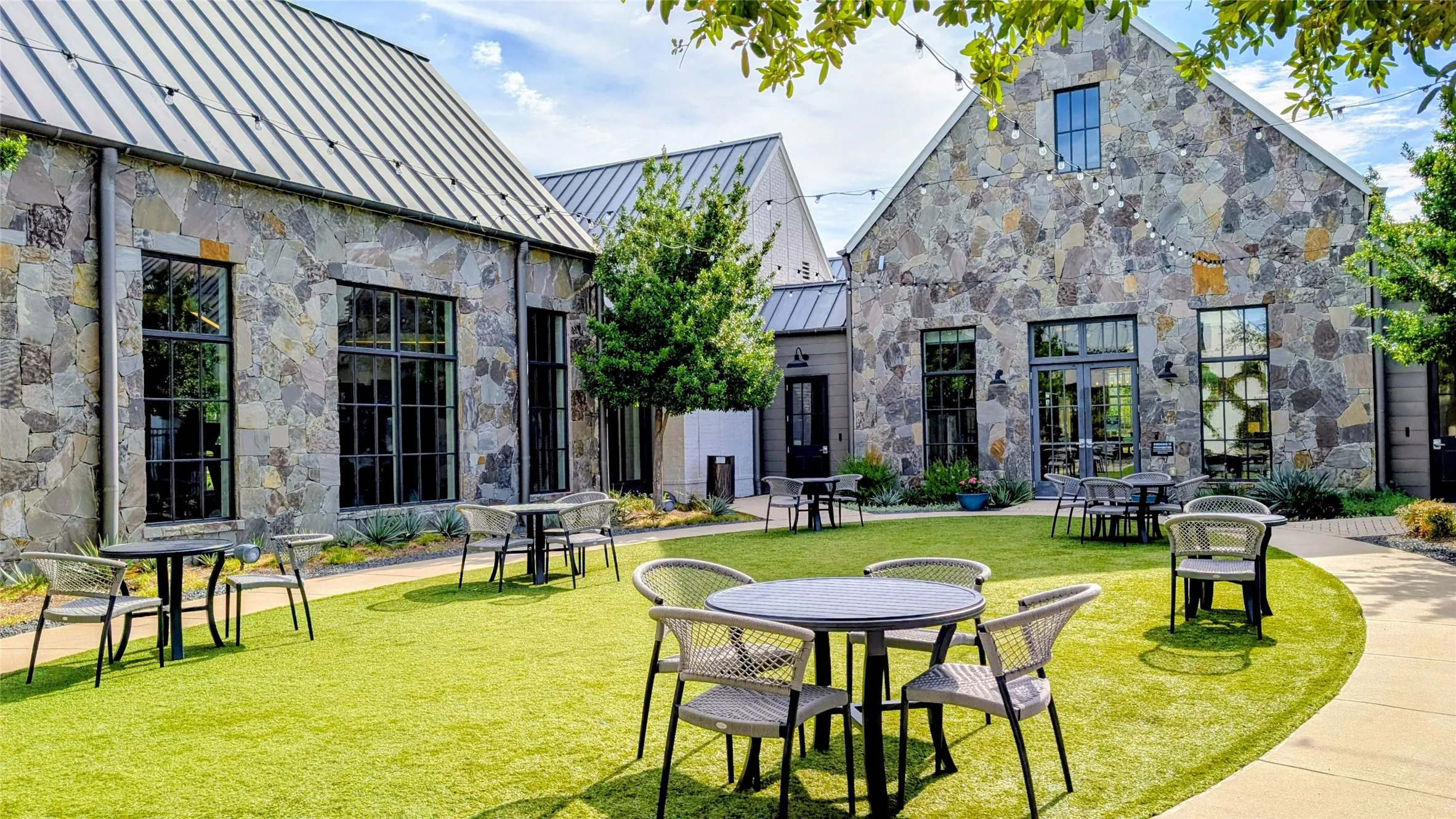 Stone-clad exterior featuring multiple large windows with dark frames, a pitched metal roof, and a central double-door entry