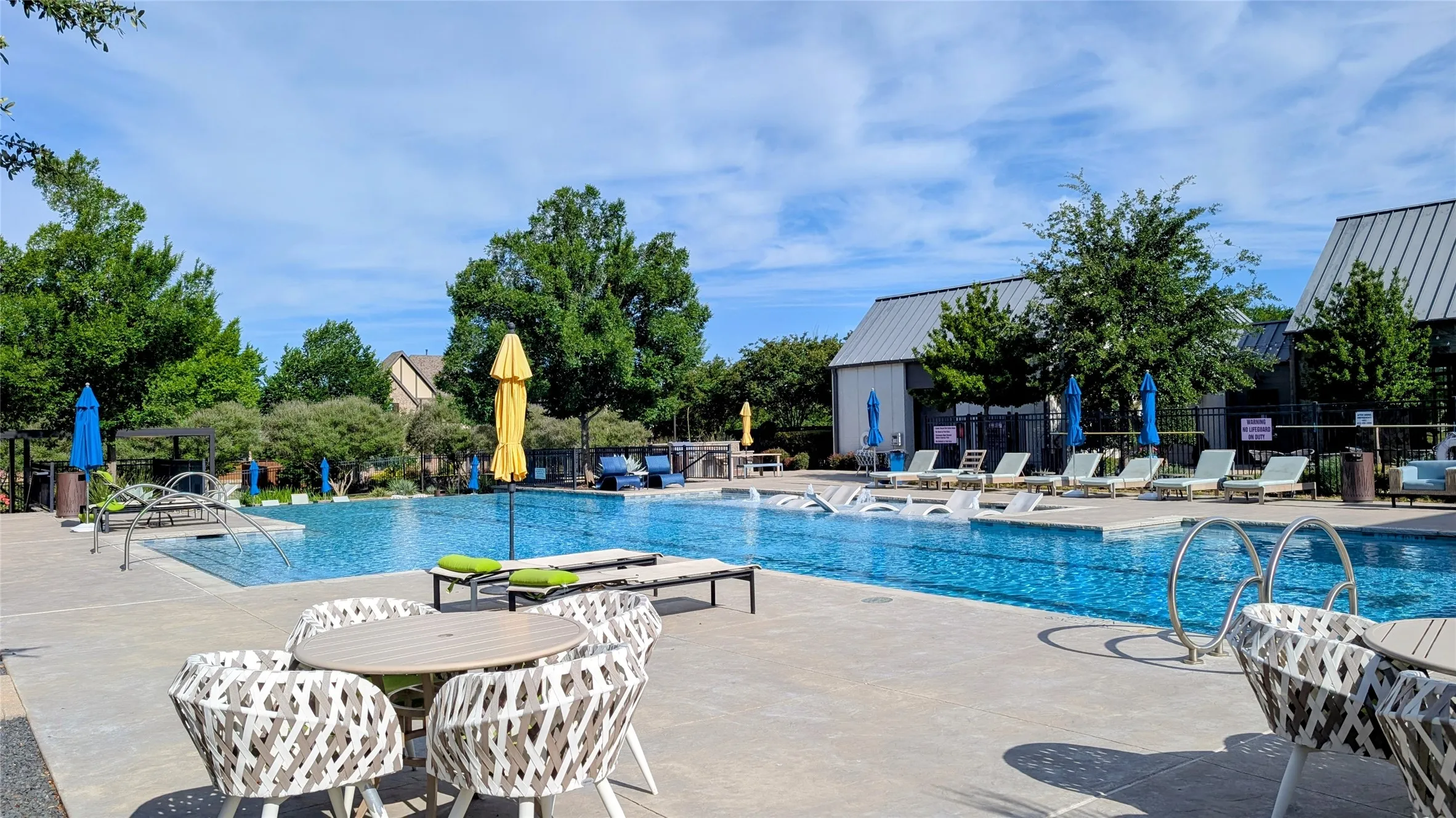 Spacious outdoor pool area featuring a large swimming pool, ample concrete decking, and multiple lounge chairs
