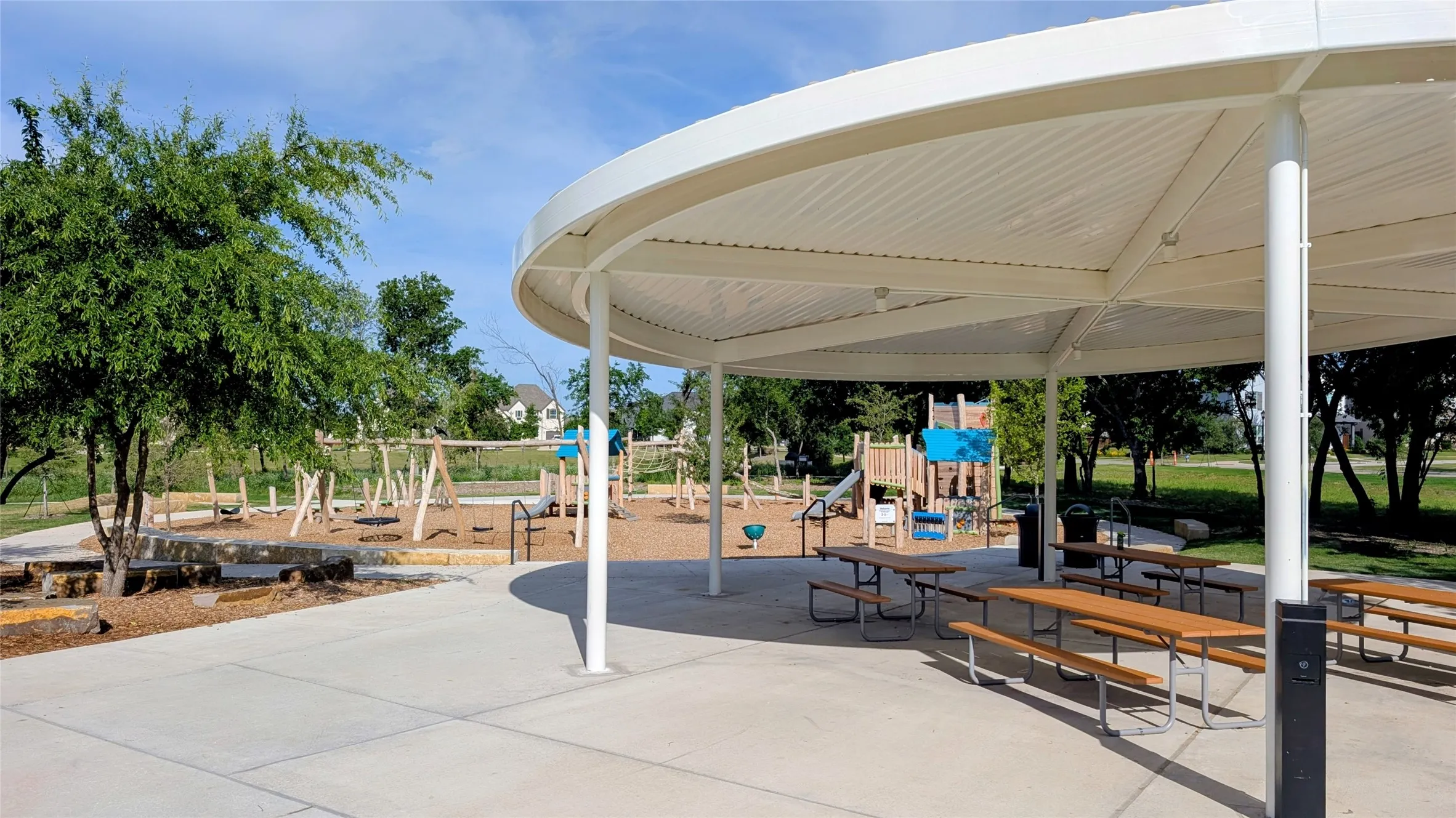 Expansive covered patio featuring multiple picnic tables and a concrete surface
