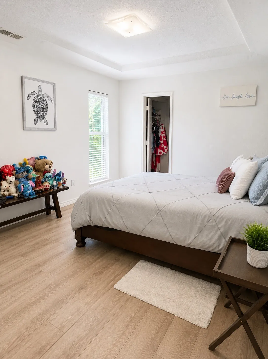 Bedroom featuring wood-finish flooring, a tray ceiling, and a window with blinds