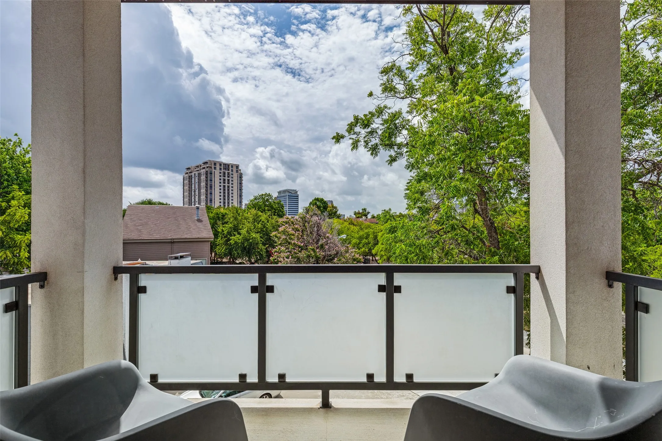 Balcony featuring frosted glass railings, a concrete floor, and stucco-finished pillars